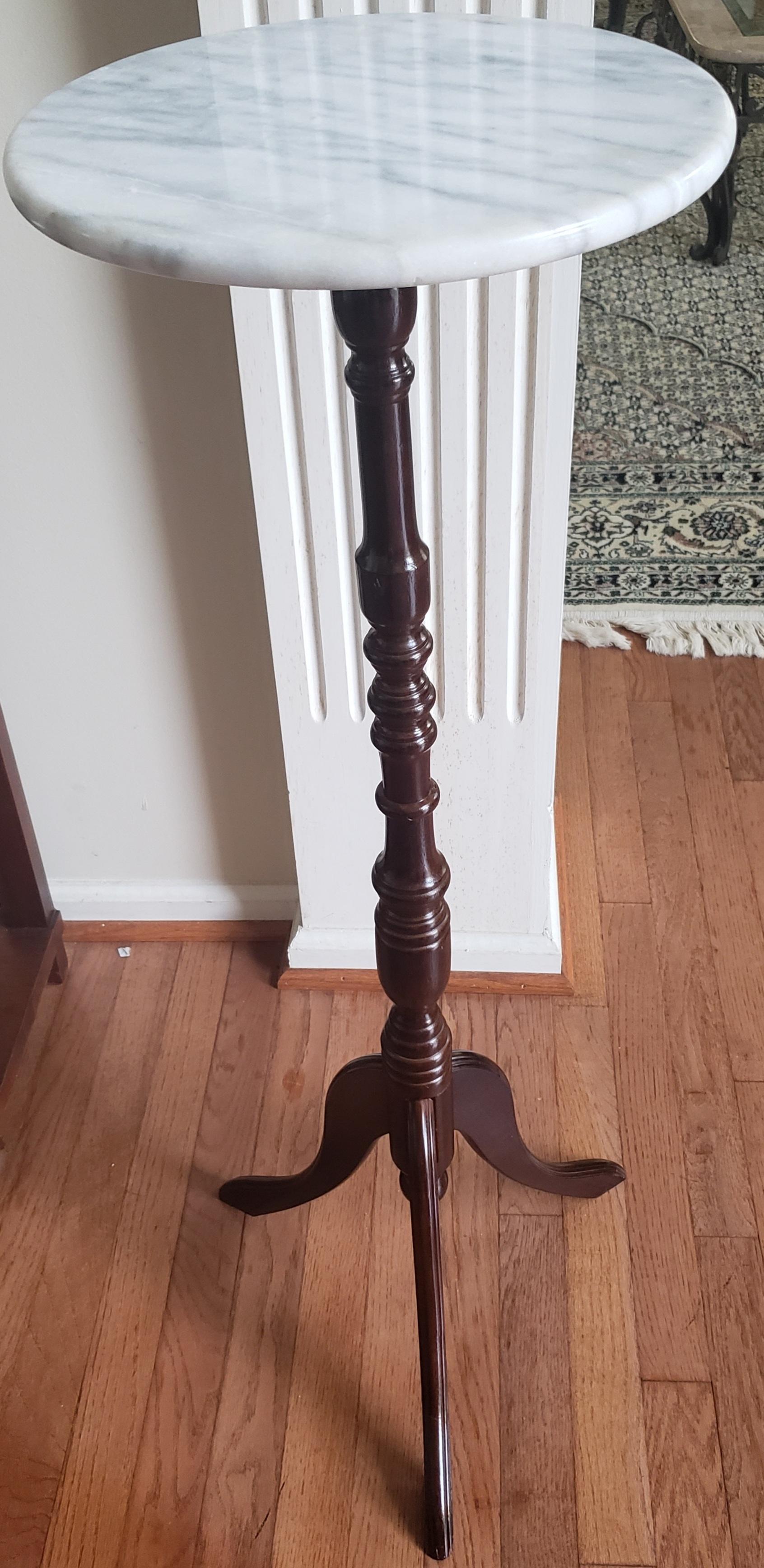 Pedestal Mahogany plant stand with tripod base. Round marble top. Turned pedestal. Measures 12.25