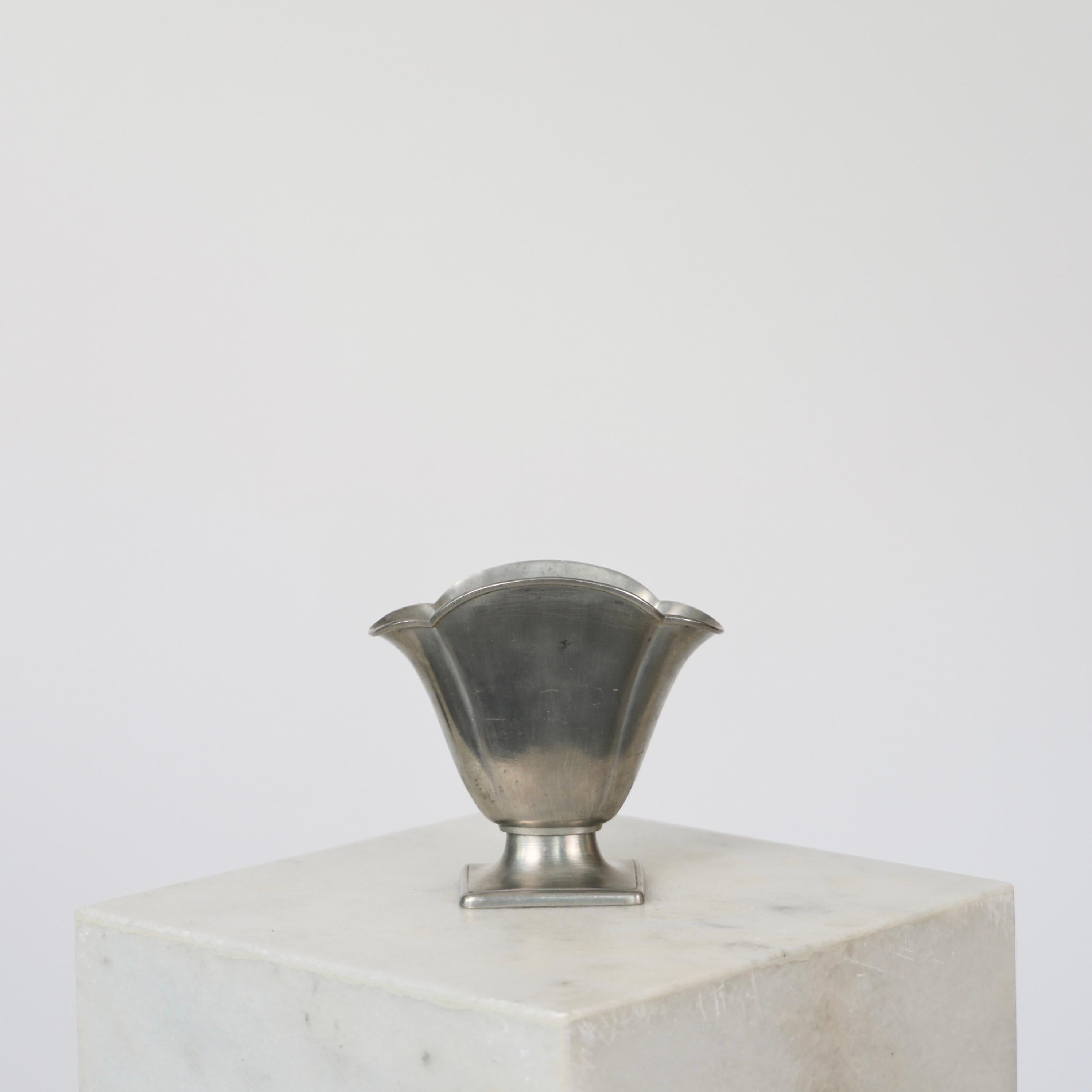 Elegant Pedestal Pewter Vase made by Just Andersen in the 1920s. 

* Fan-shaped pewter vase on square foot.
* Designer: Just Andersen
* Manufacturer: Just Andersen
* Model: 1281
* Year: 1926-1929
* Condition: Fair vintage condition. Makers engraving