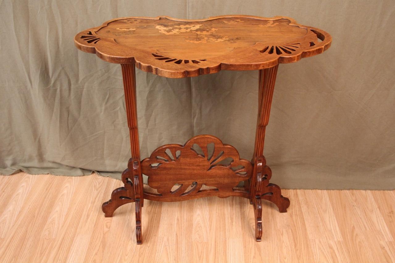 In walnut and marquetry of different types of wood, with hollow polylobed top decorated with umbelliferae. Base with two sculpted side legs. Signed in the marquetry of the tray minimal traces of wear and use Bibliography: Alastair Duncan and Georges