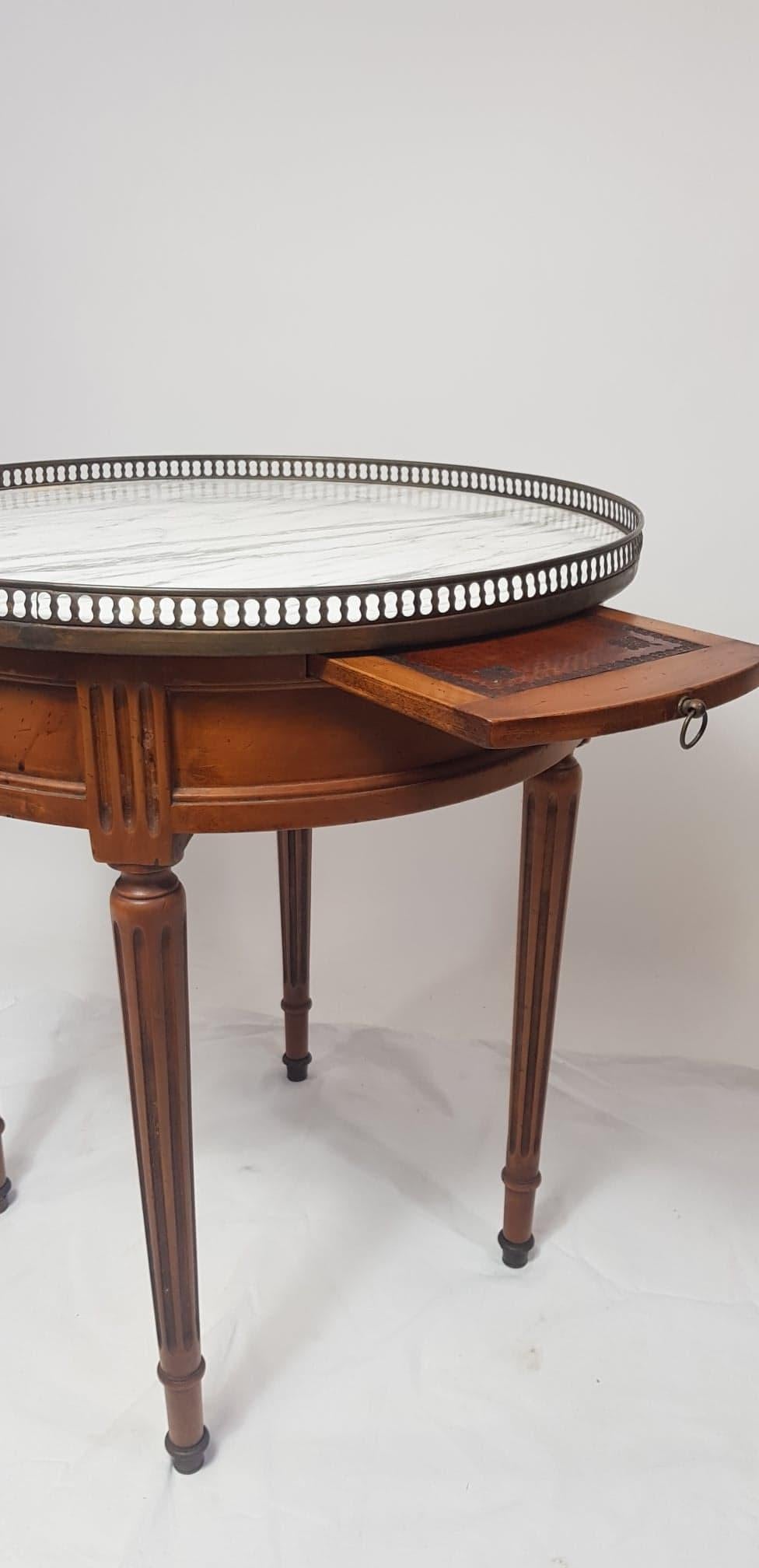 Early 20th century, Louis XVI style, bouillotte table in walnut with marble top and pierced gallery in brasse. Two drawers, and two leather covered pull-out leaves.
In perfect condition with a simple wax finish.
 