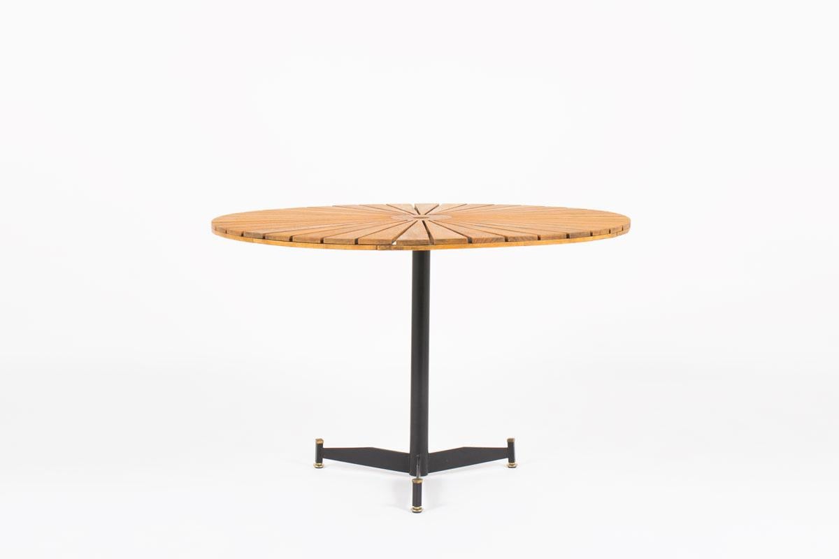 Large pedestal table designed during the 1950s in Italy. It is composed of a structure with 3 feet in black lacquered metal ended with brass elements and a round top in natural waxed teak.
The sun shape top makes this product a unique piece of