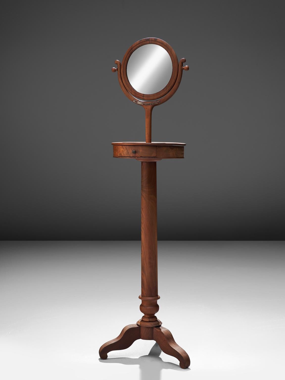 Pedestal mirror, mahogany, Italy, 1940s.

This classic piece has been executed in the finest mahogany with a waving, flowing pattern. The piece has a tripod foot. A small drawer and a small round mirror. It is the perfect piece to function as a
