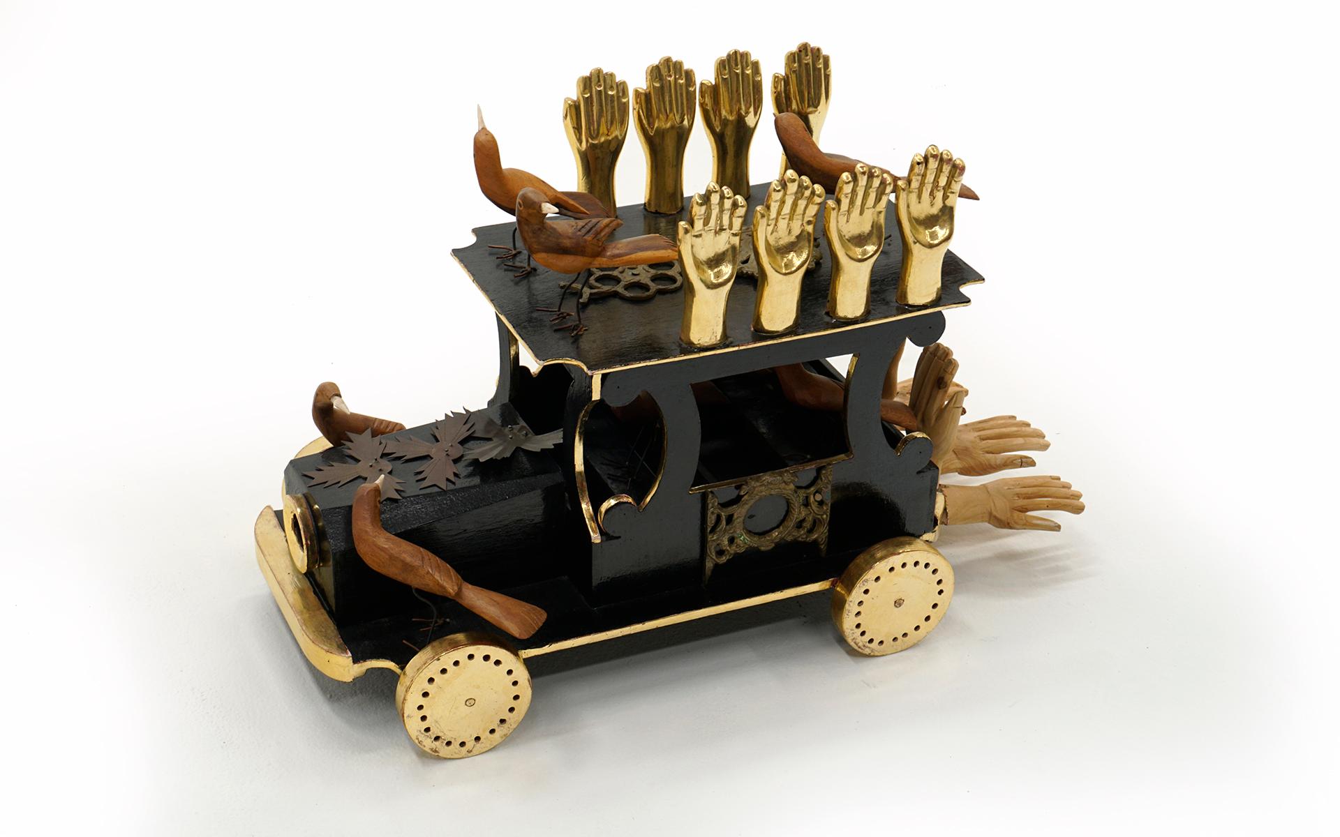 Surrealist sculpture by Mexican artist Pedro Friedeberg.  This piece was created in 1978 featuring carved and gold leaf hands, carved walnut birds, carved wood hands, and brass elements attached to the lacquered wood truck with moving wheels.  A