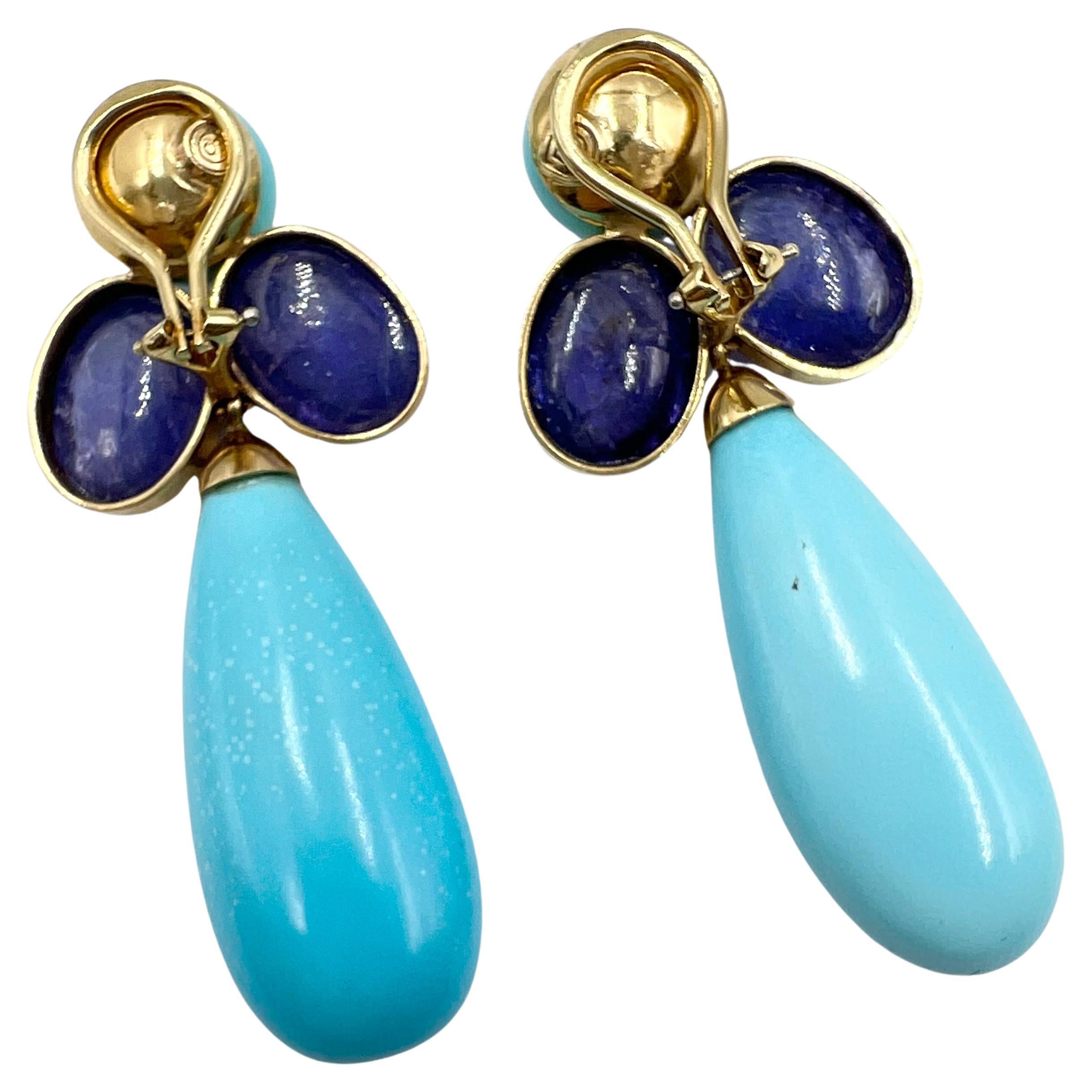 Orecchini a goccia Peggy Stephaich Guinness in oro giallo 18 carati, ognuno dei quali è caratterizzato da un turchese a forma di goccia sospeso da un grappolo di due tanzaniti ovali tagliate a cabochon con un turchese circolare tagliato a cabochon