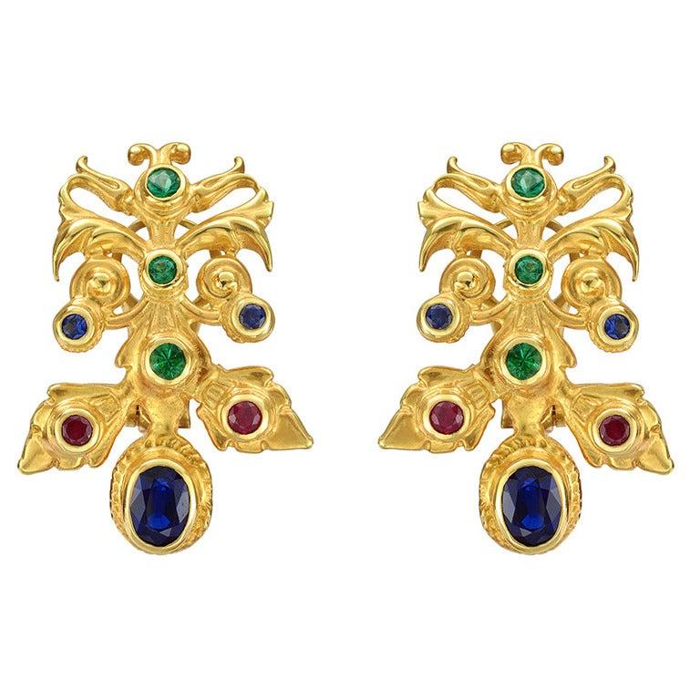 Hungarian-style earclips, set with sapphires weighing 2.31 total carats, rubies weighing 0.47 total carats and emeralds weighing 0.63 total carats, mounted in textured 18k yellow gold. Designed by Peggy Guinness.
