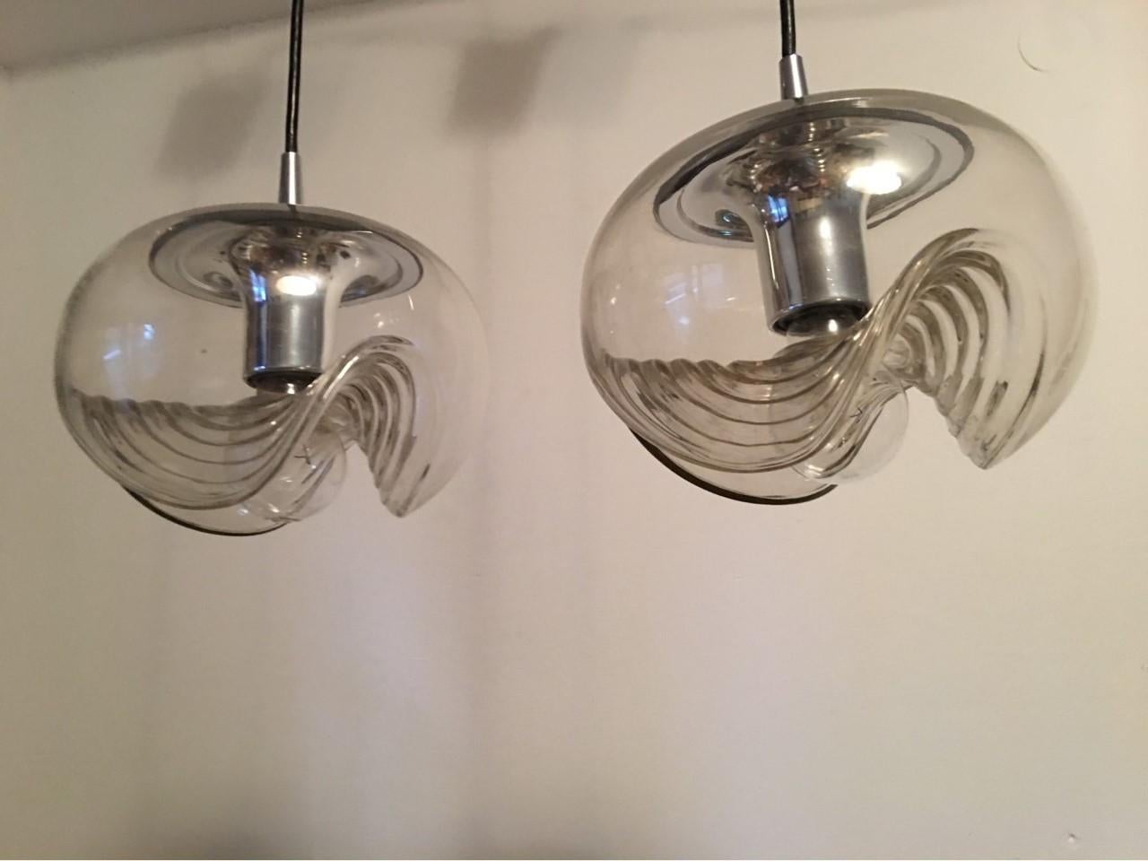 A beautiful pair of clear glass and chrome pendants from Germany. 1970s. In the USA they were also offered under the name of Koch & Lowy.
The label on these lamps shows them to be from the German manufacturer Peill & Putzler. Each requires on