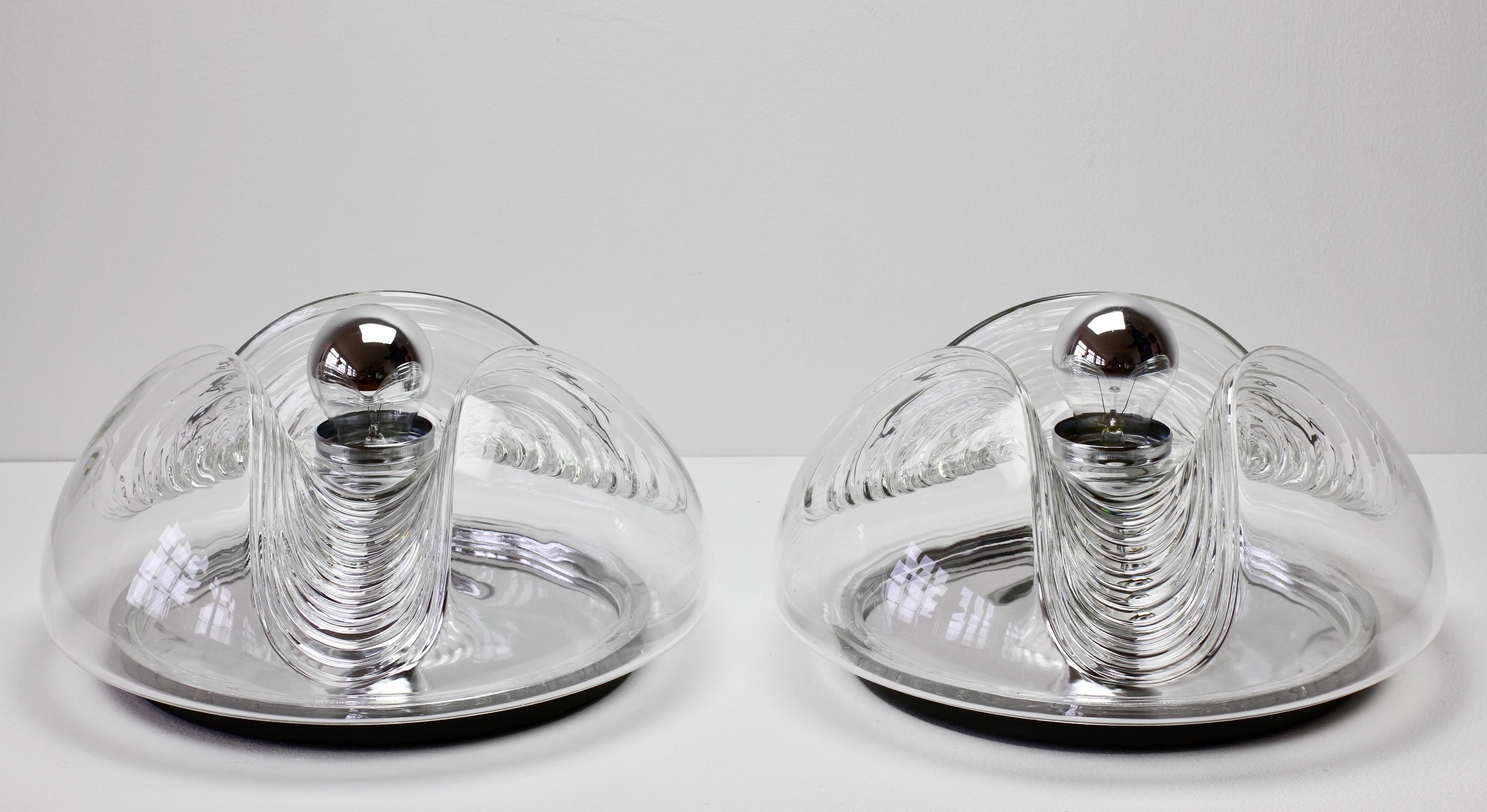 One of a pair of midcentury flushmount wall lights, lamps or sconces by Peill & Putzler in the 1970s. This is an absolutely Classic piece of German design, featuring a clear glass globe shade with a waved/ribbed molded bubble form, casting a