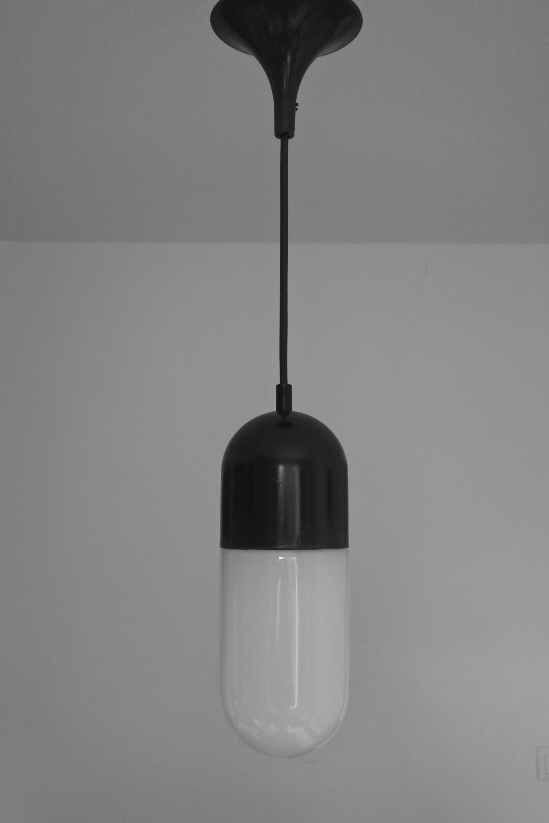 Pill shaped pendant lamp by German lamp manufacturer Peil & Putzler.
Black lacquered metal and white opal glass
6 available.
Works great as a group.
Adjustable height, as shown 130 cm, the cable can easily be shortened or changed to any greater