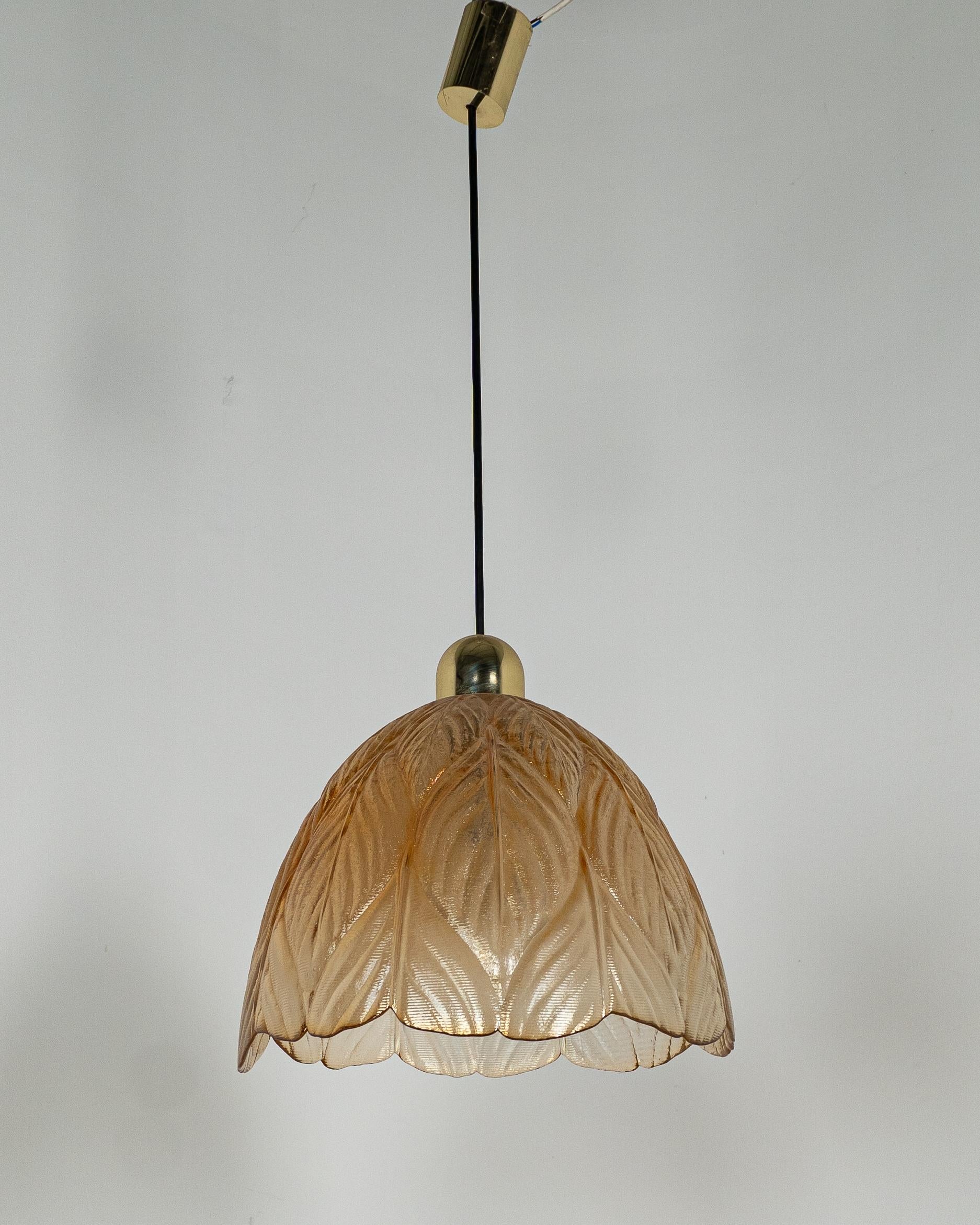Elegante lámpara colgante de la conocida marca alemana Peill & Putzler, conocida por sus diseños de cristal de alta calidad de la segunda mitad del siglo XX. Este modelo presenta un cristal texturizado en un cálido tono marrón dorado, con un bonito