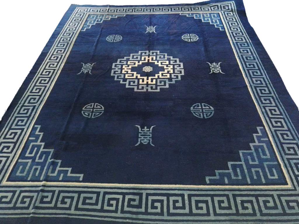 Blue and white is always fashionable and in this circa 1900 Peking Chinese carpet it is applied in a restrained , sophisticated manner with a complex, bitonal fret medallion floating with “shou” and other quasi-calligraphic symbols, within bold