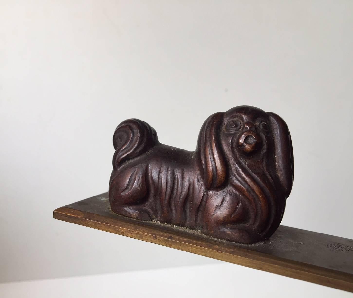 Very heavy desk ornament or paperweight composed of patinated bronze. Its depicting a Pekingese dog and a cat. It was manufactured in Scandinavia during the late 1920s or early 1930s.