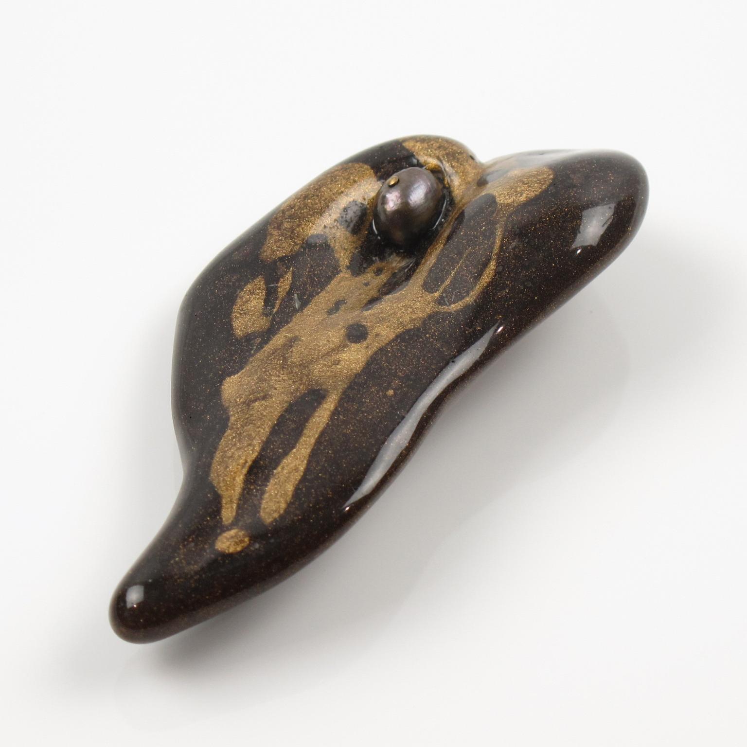 Questa bellissima spilla Donatella Pellini Italy presenta un design couture con una forma libera modernista. La resina marrone cacao presenta inclusioni dorate ed è sormontata da una perla d'acqua dolce nera. Il pezzo è firmato sul retro con il logo