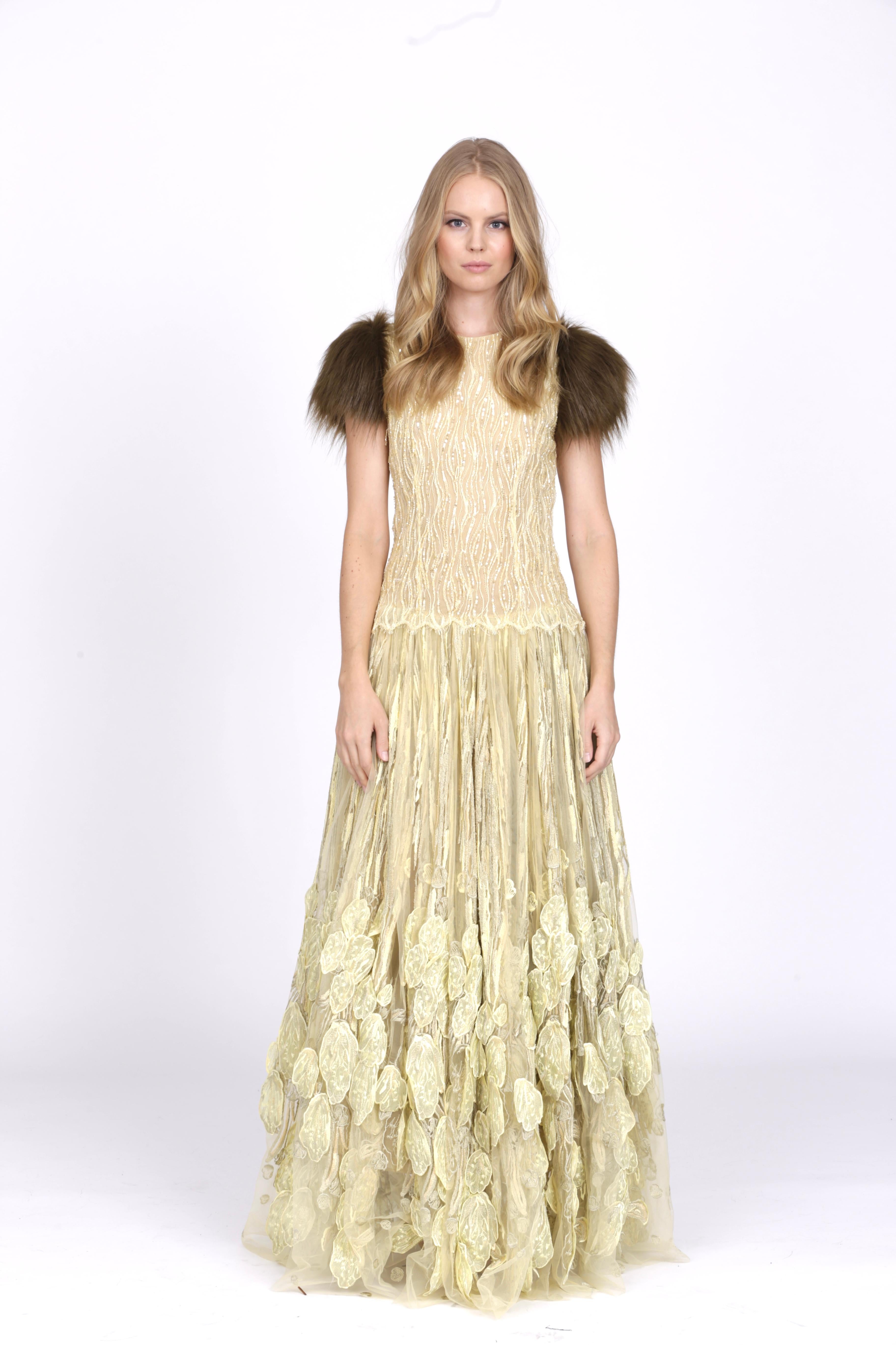 The Grace Pelush citrine tulle evening gown dress with faux fur cap sleeves is a one of a kind exclusive piece. Featuring handmade embroidery of sparkling sequence and beads, it cascades into beautiful floral petals with multi shades of golden