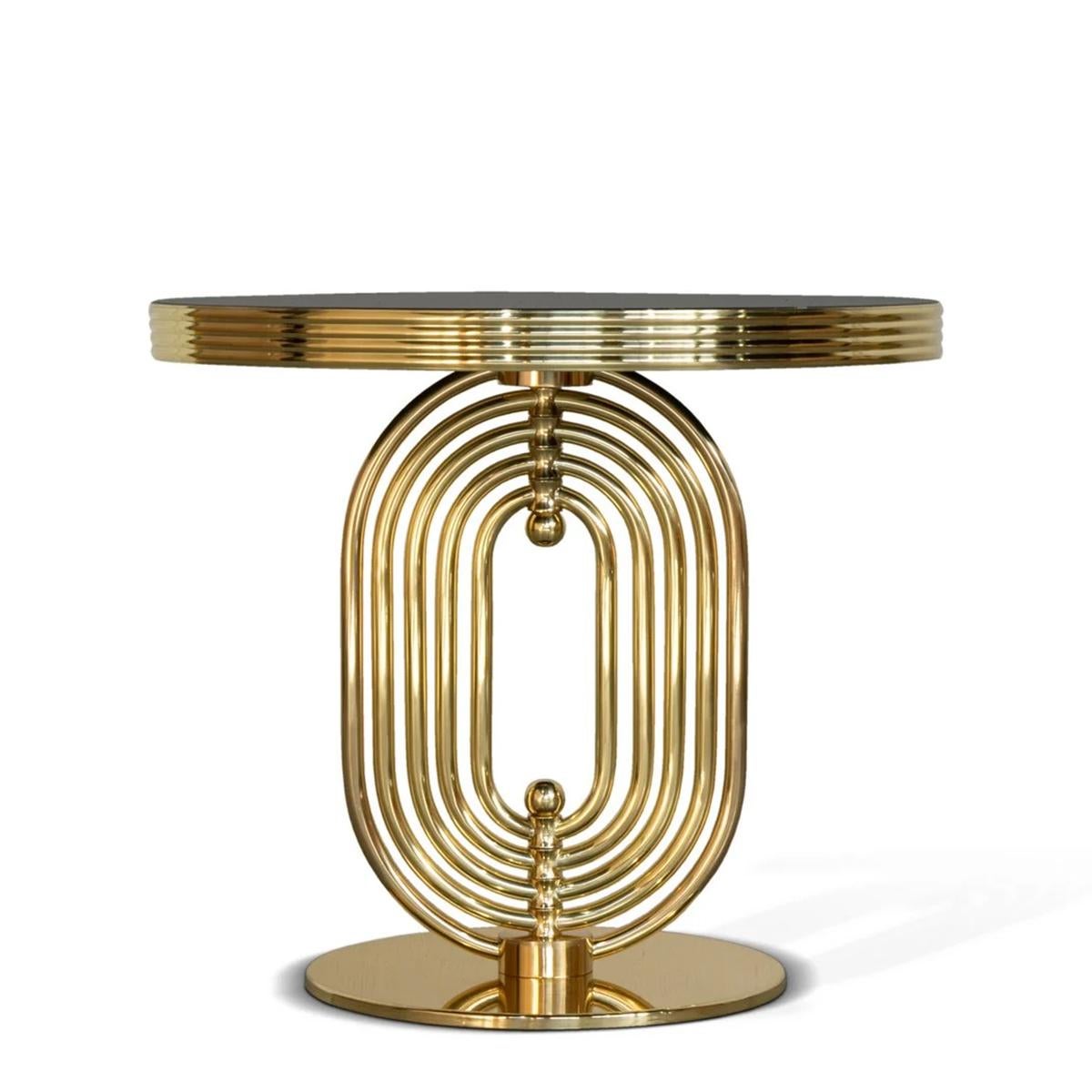 Round Table Pema with structure in solid brass in polished 
finish, with rotating elements on the pole of the base. With
polished black marble round top.