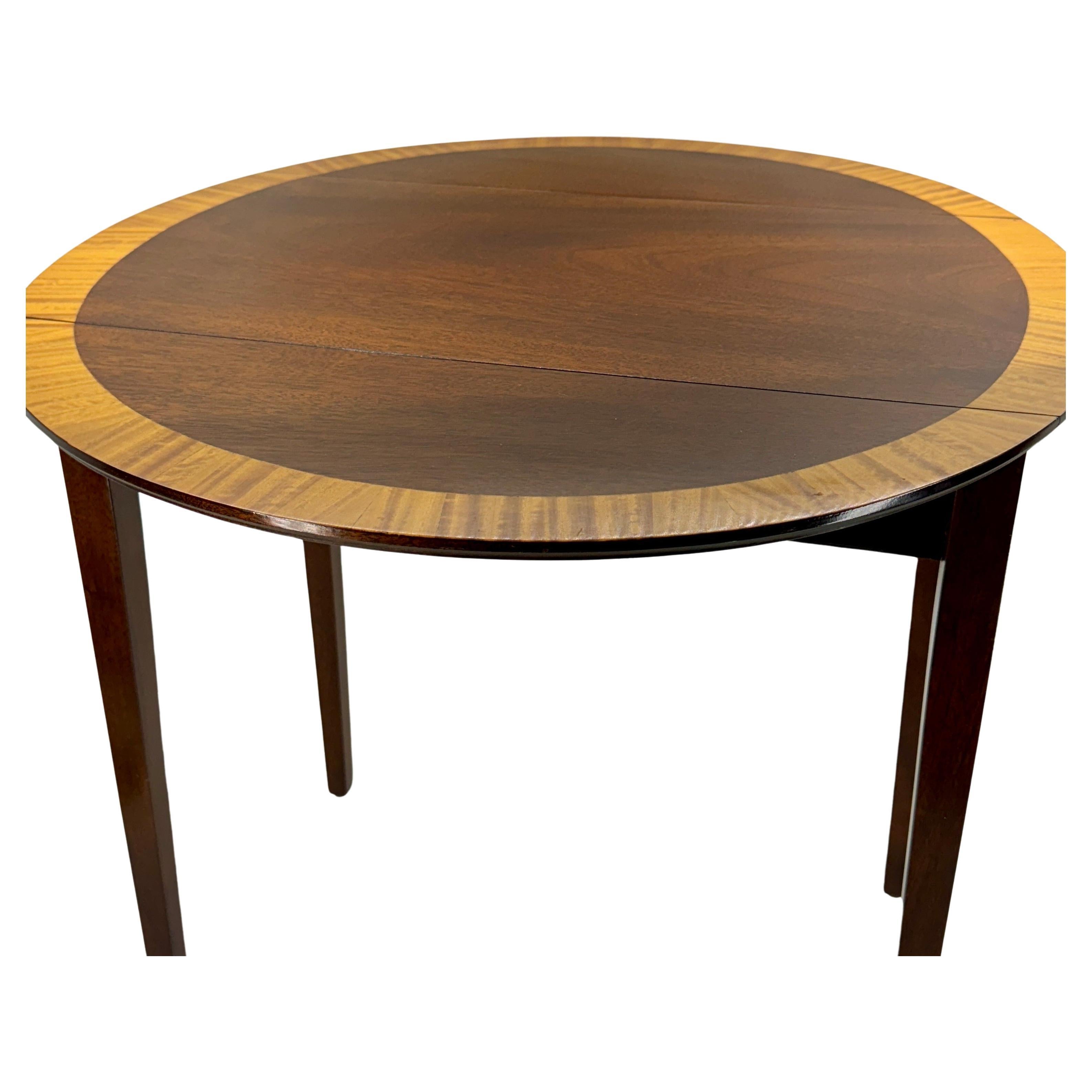 Klassischer kleiner Pembroke-Mahagoni-Tisch mit einer satinierten Holzplatte und einer Schublade. Dieses Stück steht auf hohen, quadratischen, spitz zulaufenden Beinen und wird an den Seiten von zwei ovalen Fächern aus satiniertem Holz flankiert.