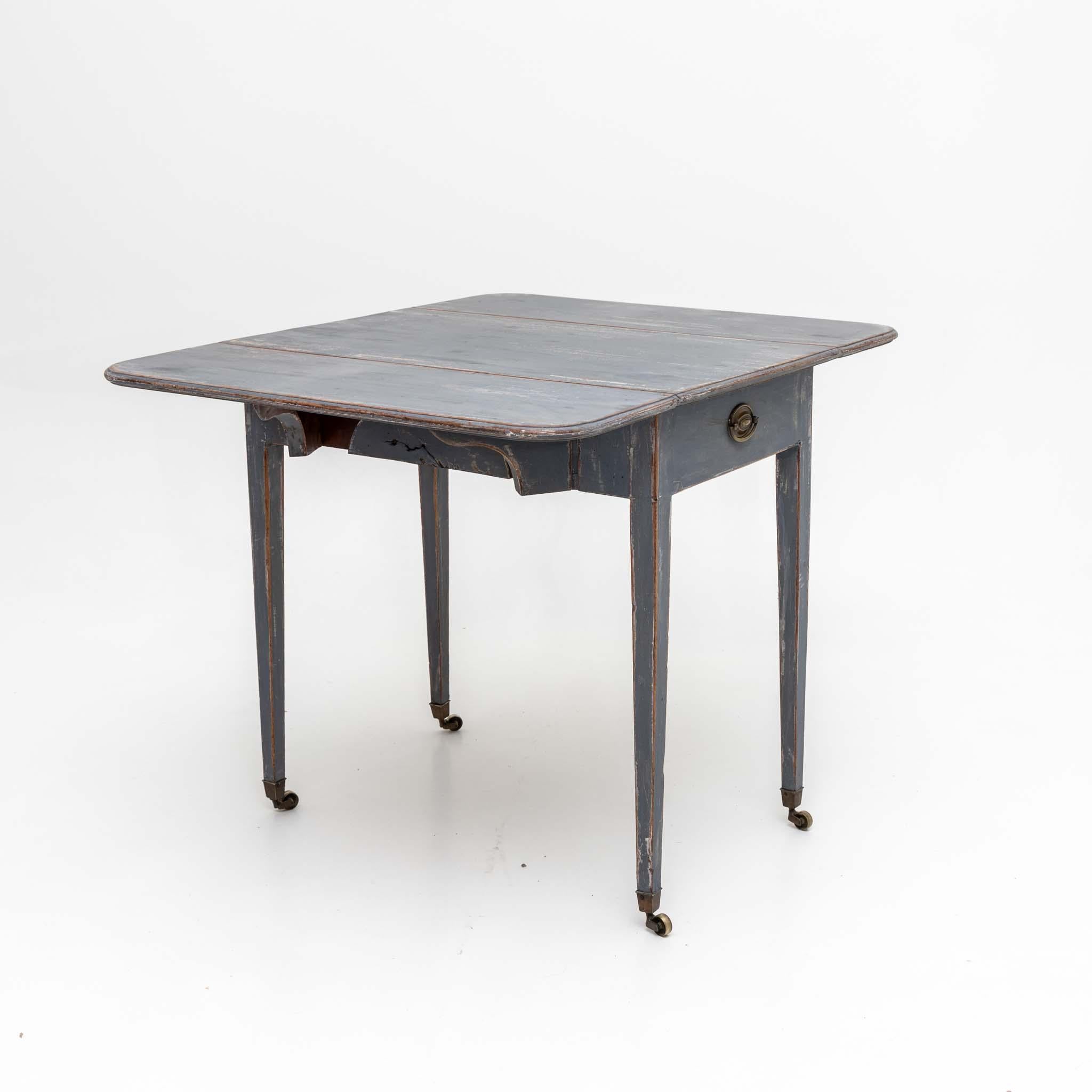 Table avec côtés pliants reposant sur quatre pieds coniques avec roulettes. La peinture bleue est neuve et décorativement patinée.