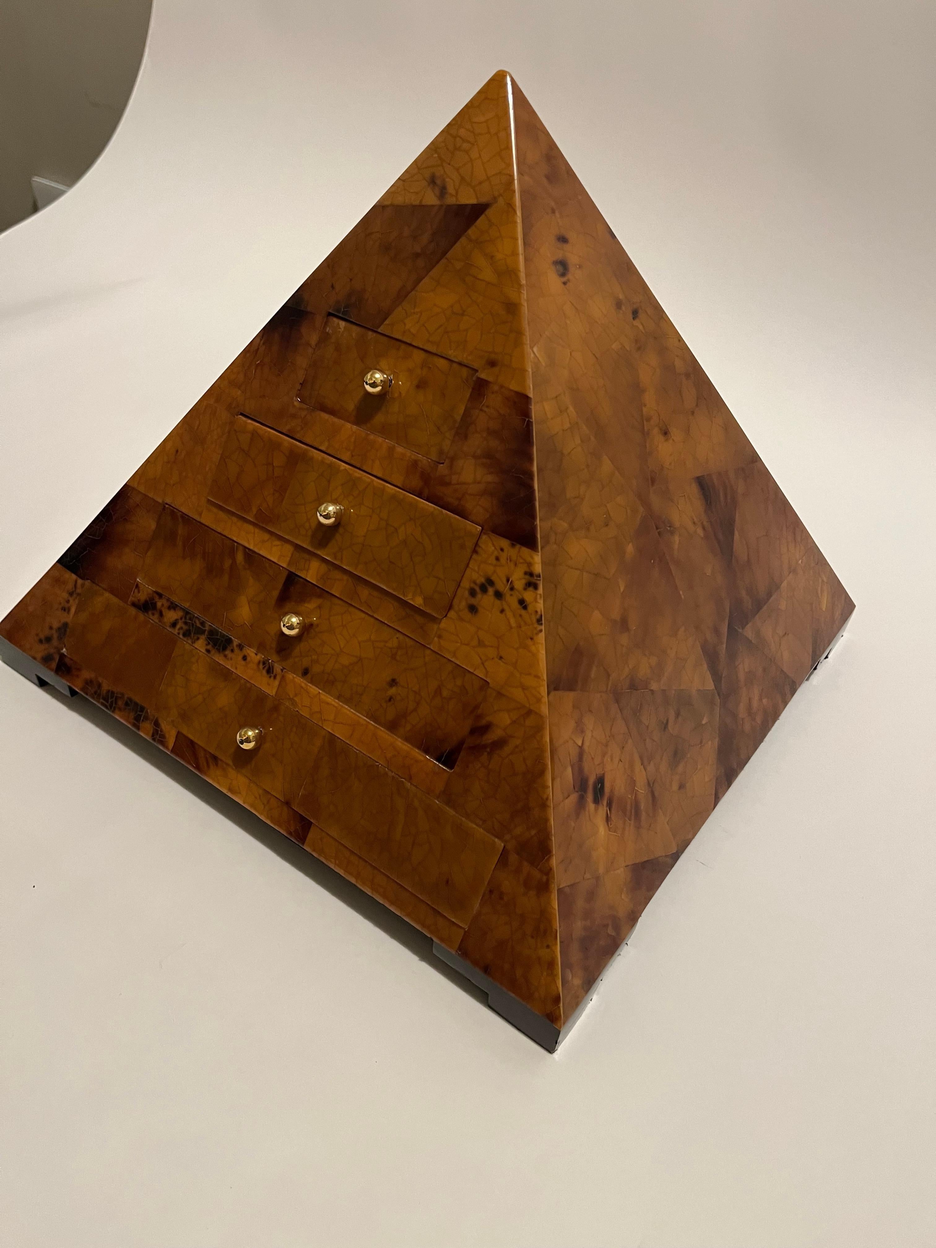 A pyramid shaped box having 4 graduating drawers with brass ball knobs . Made of polished pen shell which is a material that the manufacturer Maitland Smith often used. All sitting upon ogee feet with a felt undersided