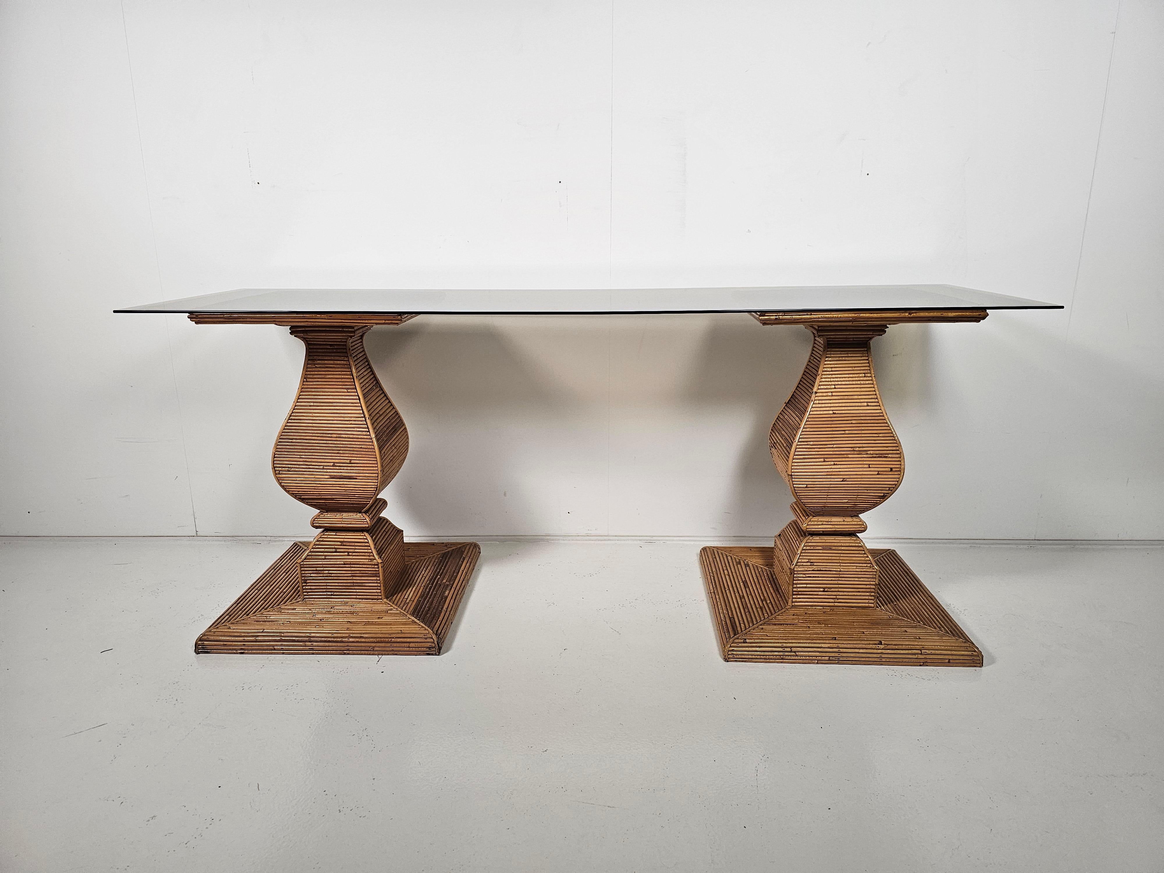 Fabulous console table in the style of Gabriella Crespi or Vivai del Sud from the 1970s. Consisting of twp pencil rattan-wrapped baluster pedestal bases and heavy tempered smoked glass top. The top can come of. So they can also be used as just
