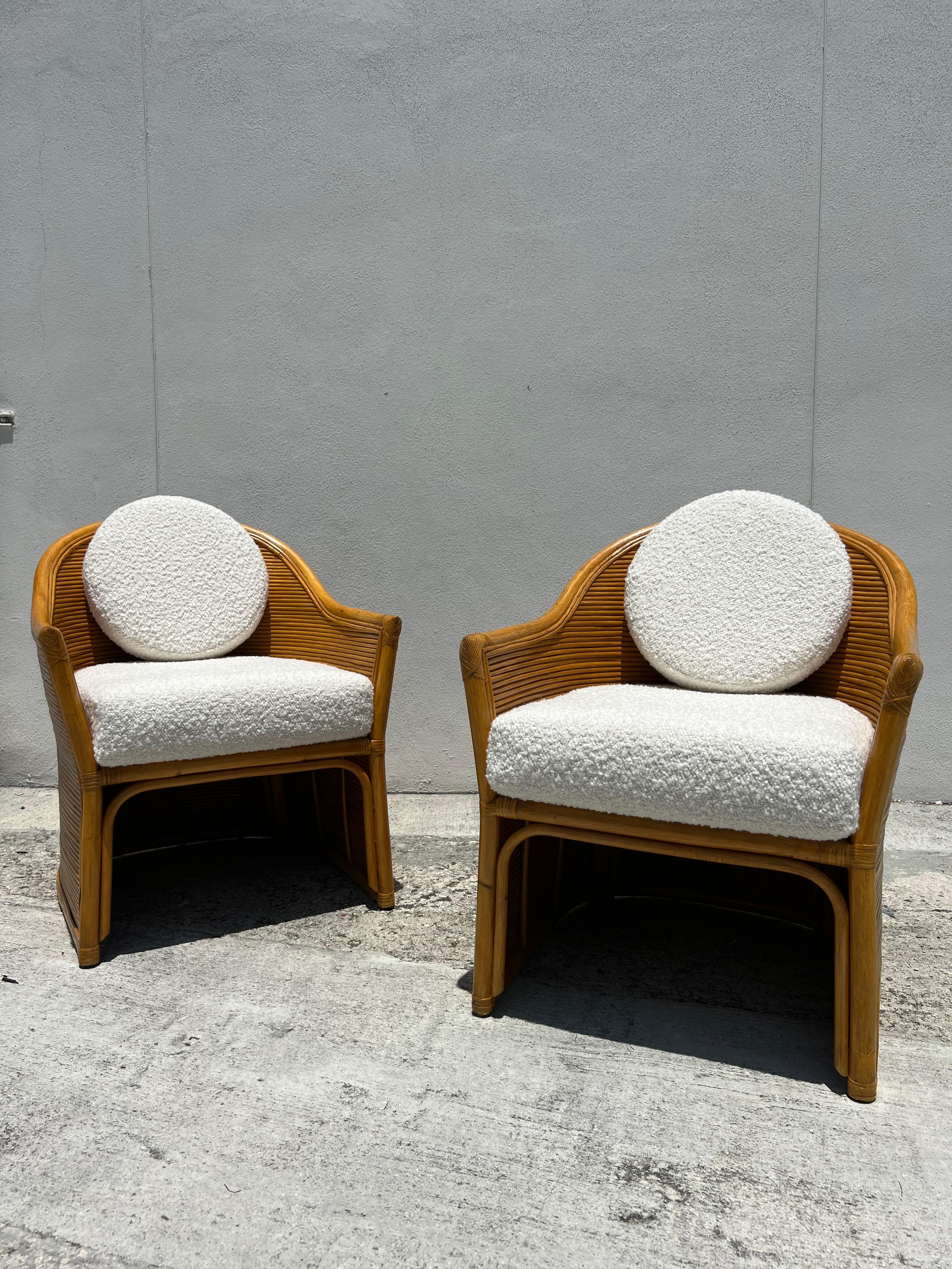 Beautiful pencil reed and rattan wrapped clubbed chairs refinished in excellent condition. Newly upholstered custom round back cushions as well as seats have been added in a rich ivory bouclé. This stunning pair is ready to be placed.