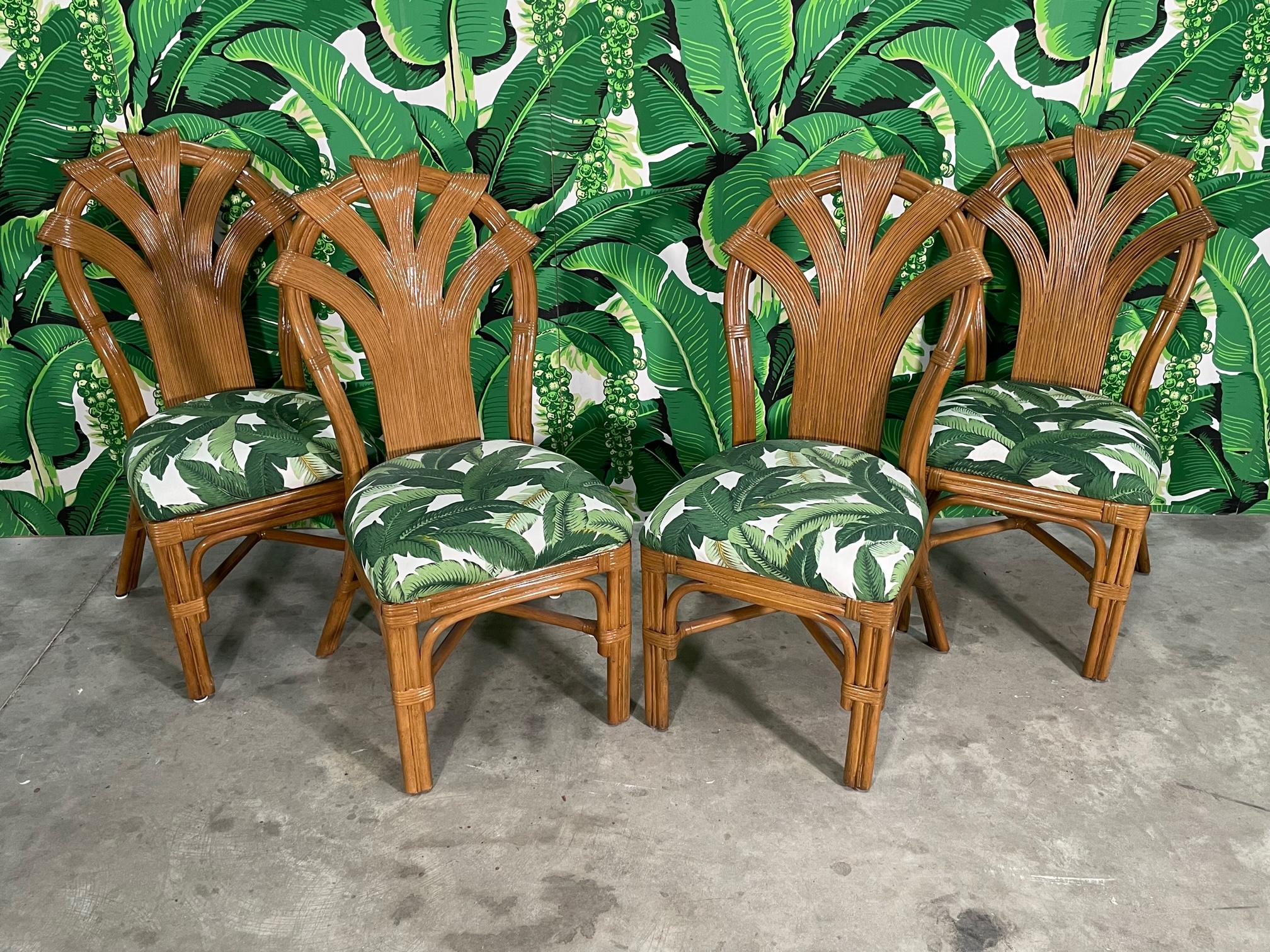 Set of four rattan dining table chairs feature ribbon style pencil reed forms in the style of Betty Cobonpue. Upholstered in Tommy Bahama 