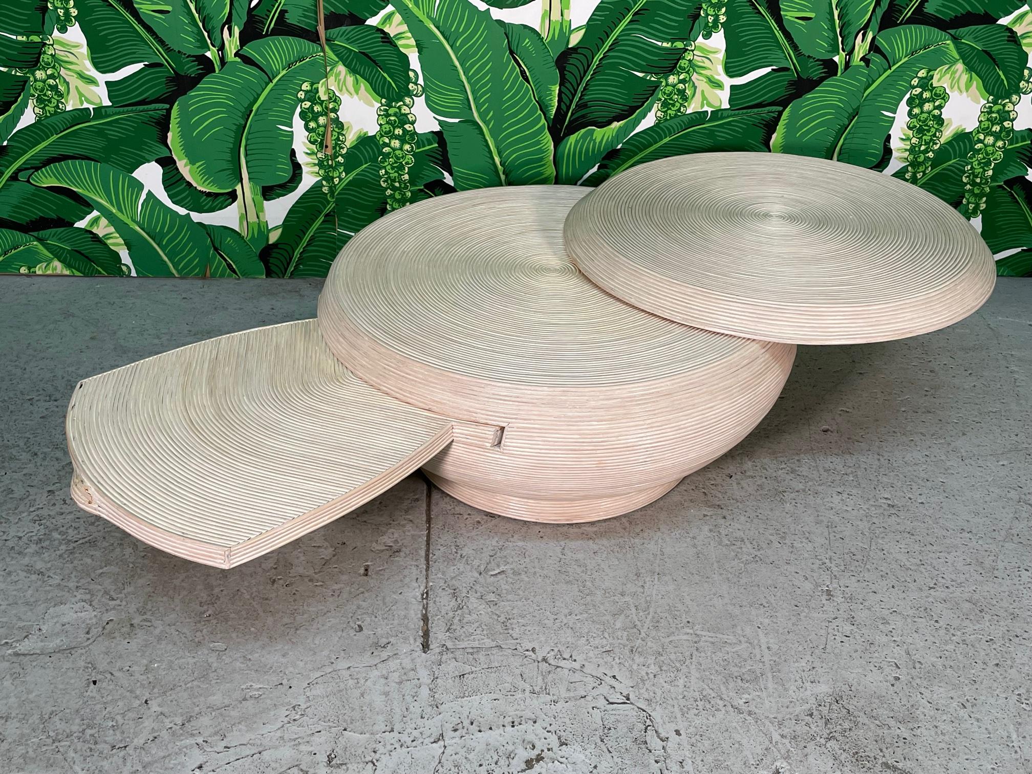 Vintage sculptural coffee table features a unique spherical form and full veneer of pencil reed rattan. Top rotates to expand surface area and hidden shelf pulls out from side. Similar to the split reed veneers of Gabriella Crespi and Betty