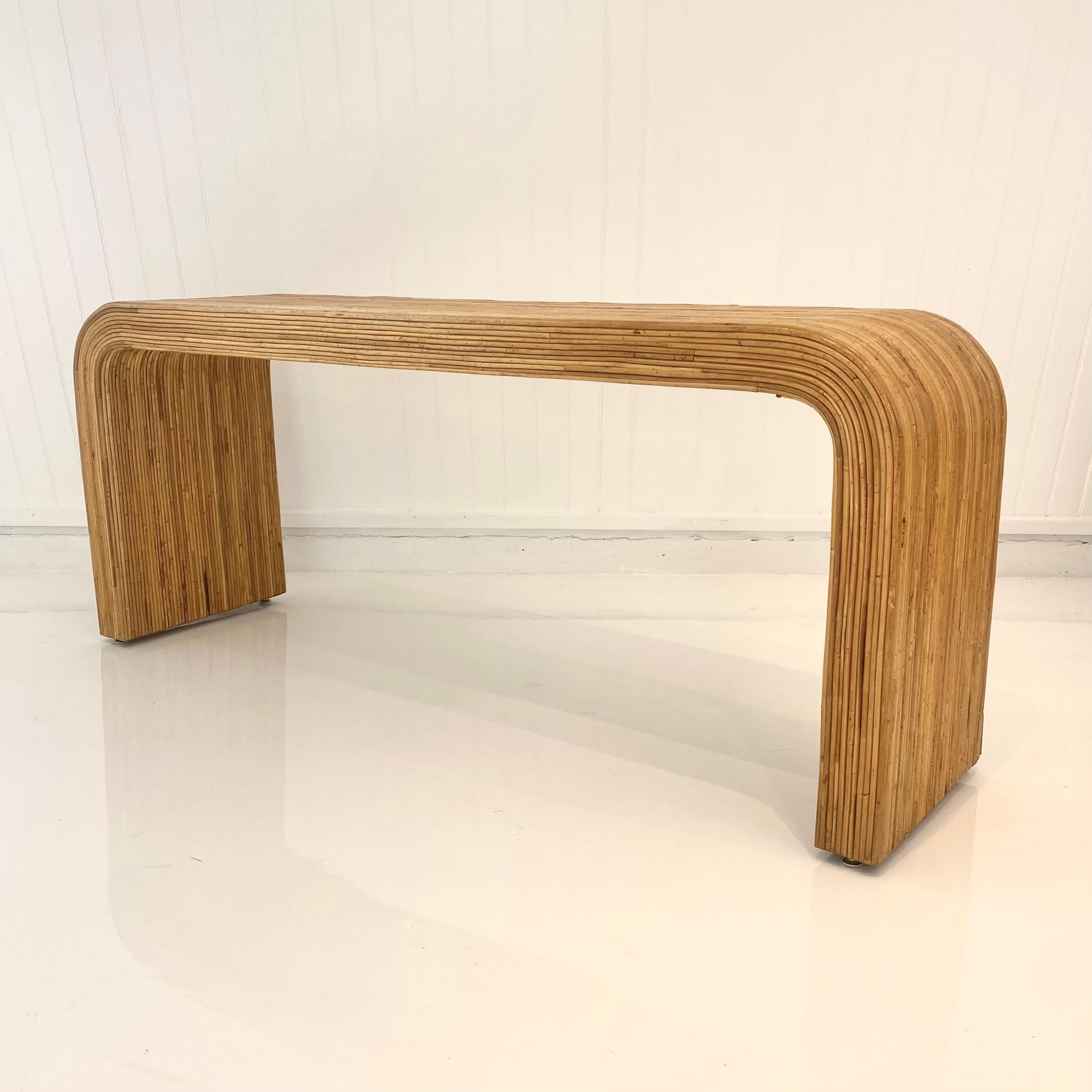 Magnifique console à cascade en roseau, vers les années 1970. Grande taille, inhabituelle. Les bords arrondis organiques confèrent à cette pièce une personnalité tranquille et éclectique. Les anches sont minutieusement et discrètement clouées à la