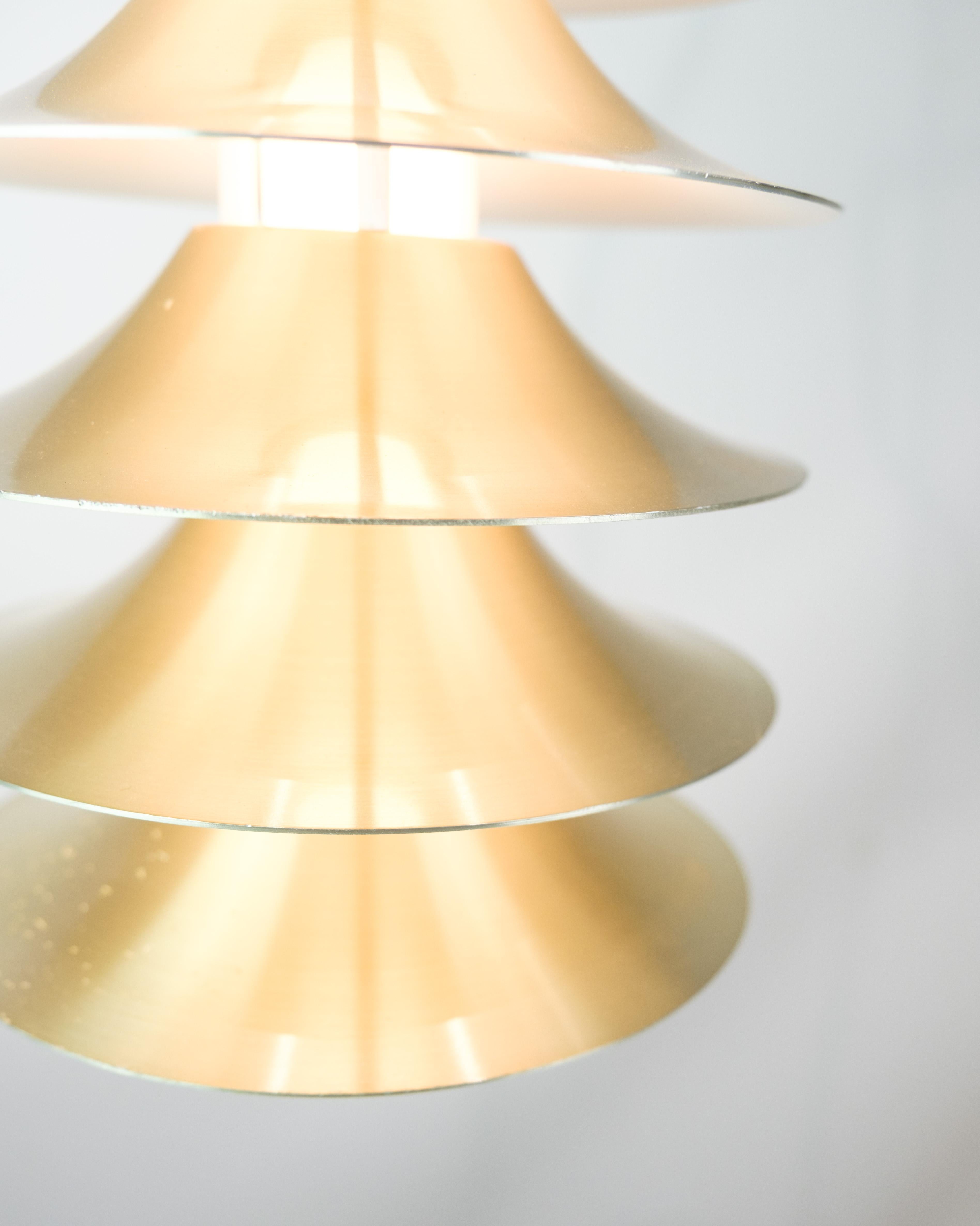 This vintage pendant light, crafted from aluminum and featuring several layers, epitomizes the innovative and distinctive style of Danish design from around the 1970s. With its unique layered design, this pendant light adds depth and visual interest