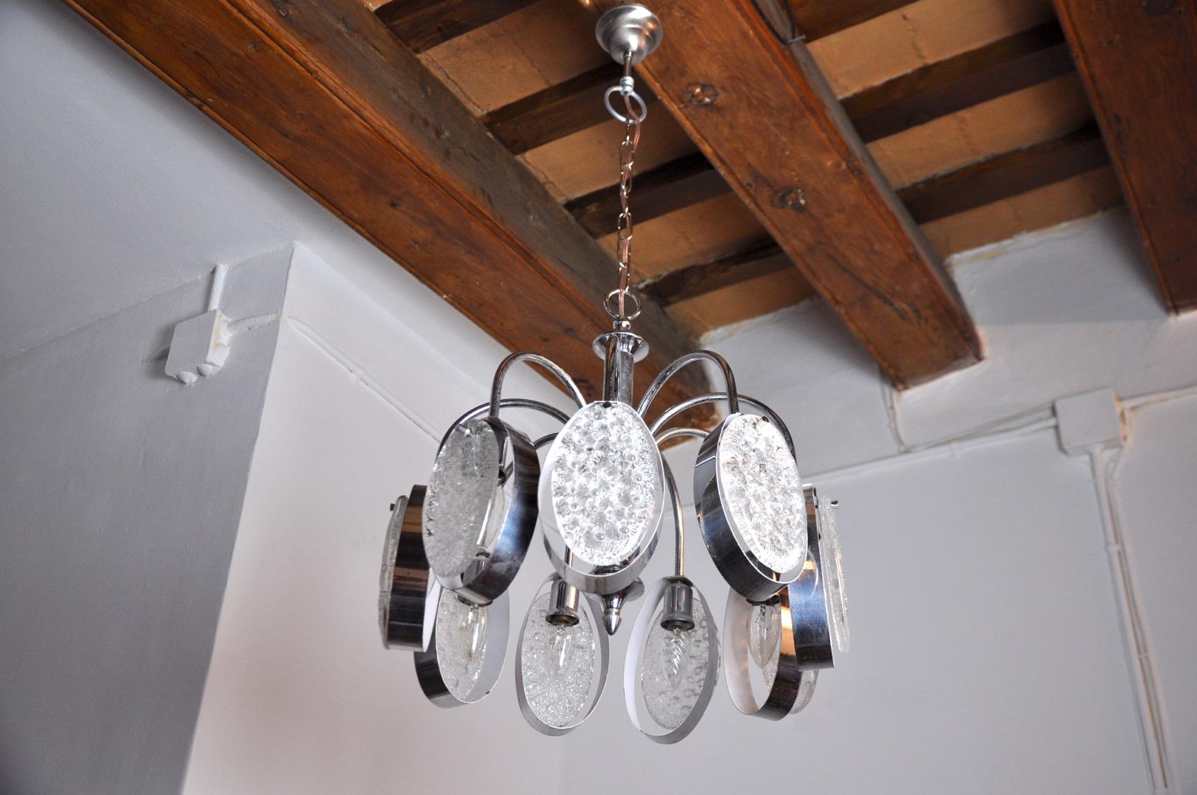 Superbo lampadario attribuito a Gaetano Sciolari progettato e prodotto in Italia negli anni '70. Struttura cromata composta da 9 cristalli smerigliati in perfetta conservazione distribuiti su 9 bracci. Un raro oggetto di design che illuminerà