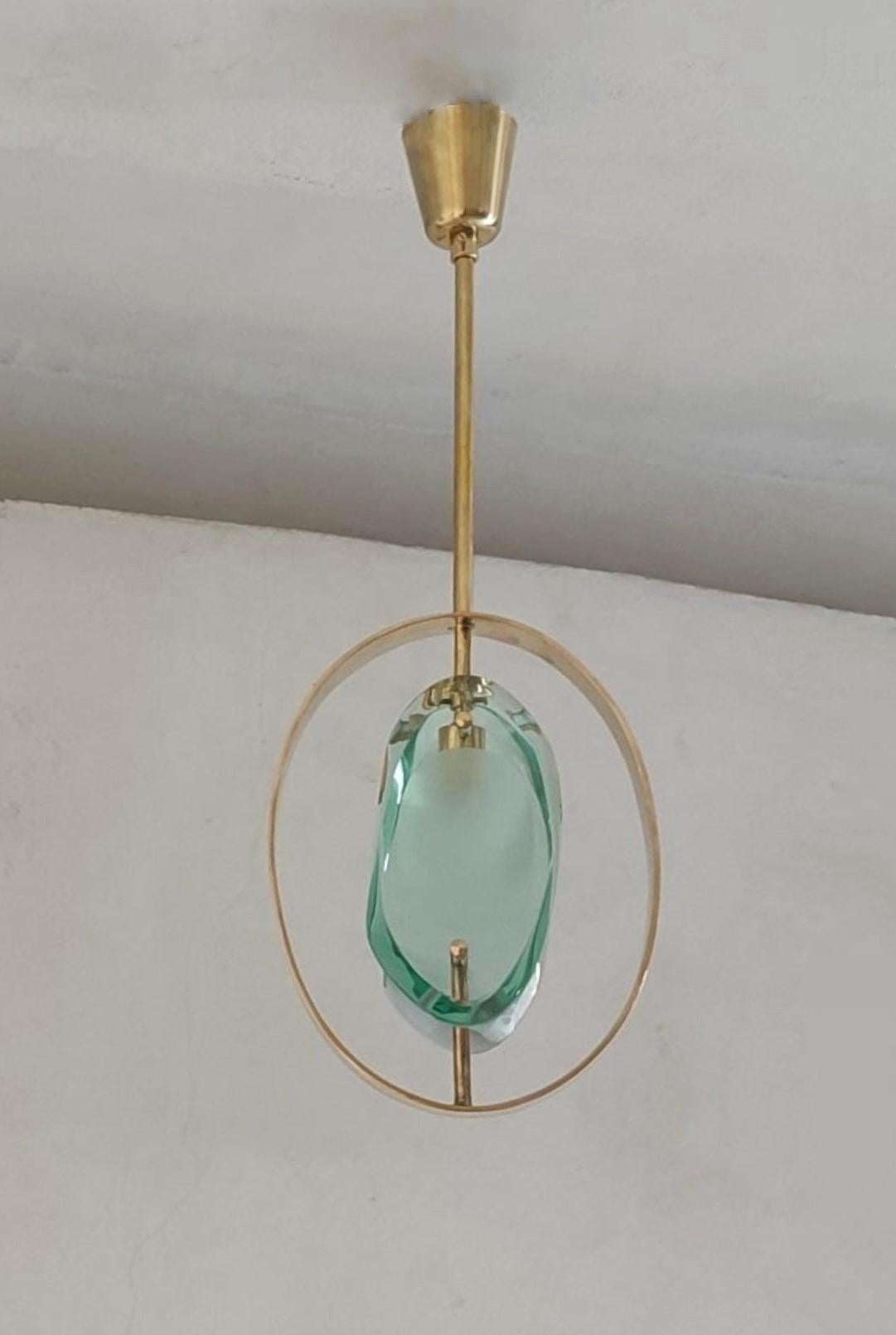 An iconic design pendant by Max Ingrand for Fontana Arte, Model 1933, Italy, 1961. Organically shaped double lens cut panels of thick profiled polished Murano glass with sandblasted centers fitted within a natural brass ring suspended from brass
