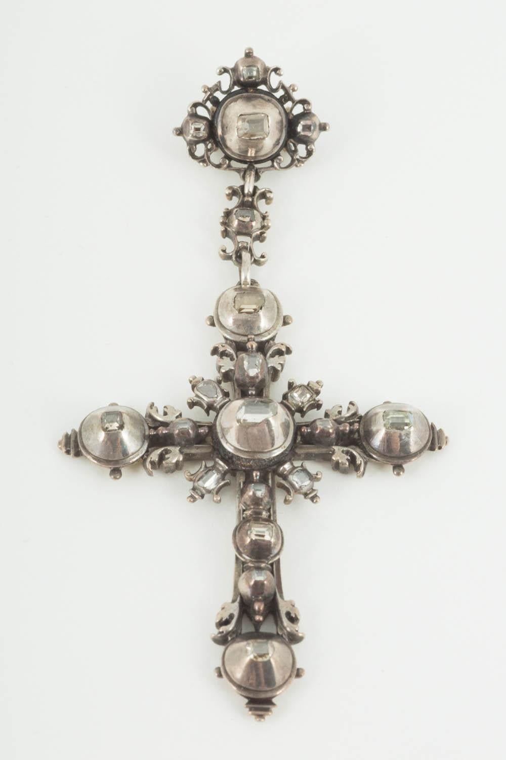 A rare antique piece dating back to the early 18th century of a silver cross set with 20 table cut diamonds, all of them foiled backed which is typical of the period. The pendant has a beautiful scrolled floral design and is substantial in