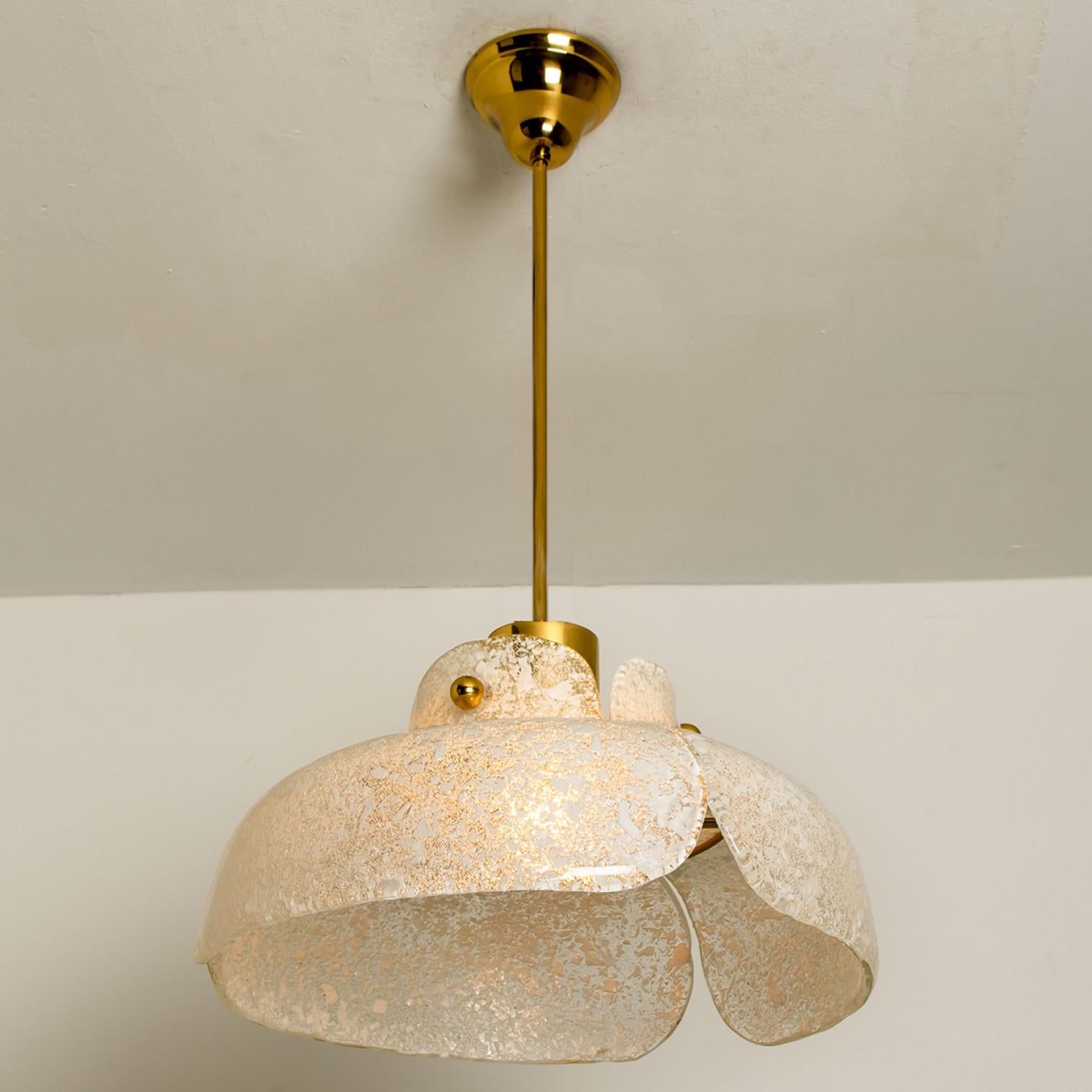 Beautiful pendant lamp in the shape of a flower. In the style of Kalmar.
Three leaf-like pieces of thick speckled glass are wrapped around a glossy brass base.
The light shining trough the glass gives special effect.

In excellent vintage condition.