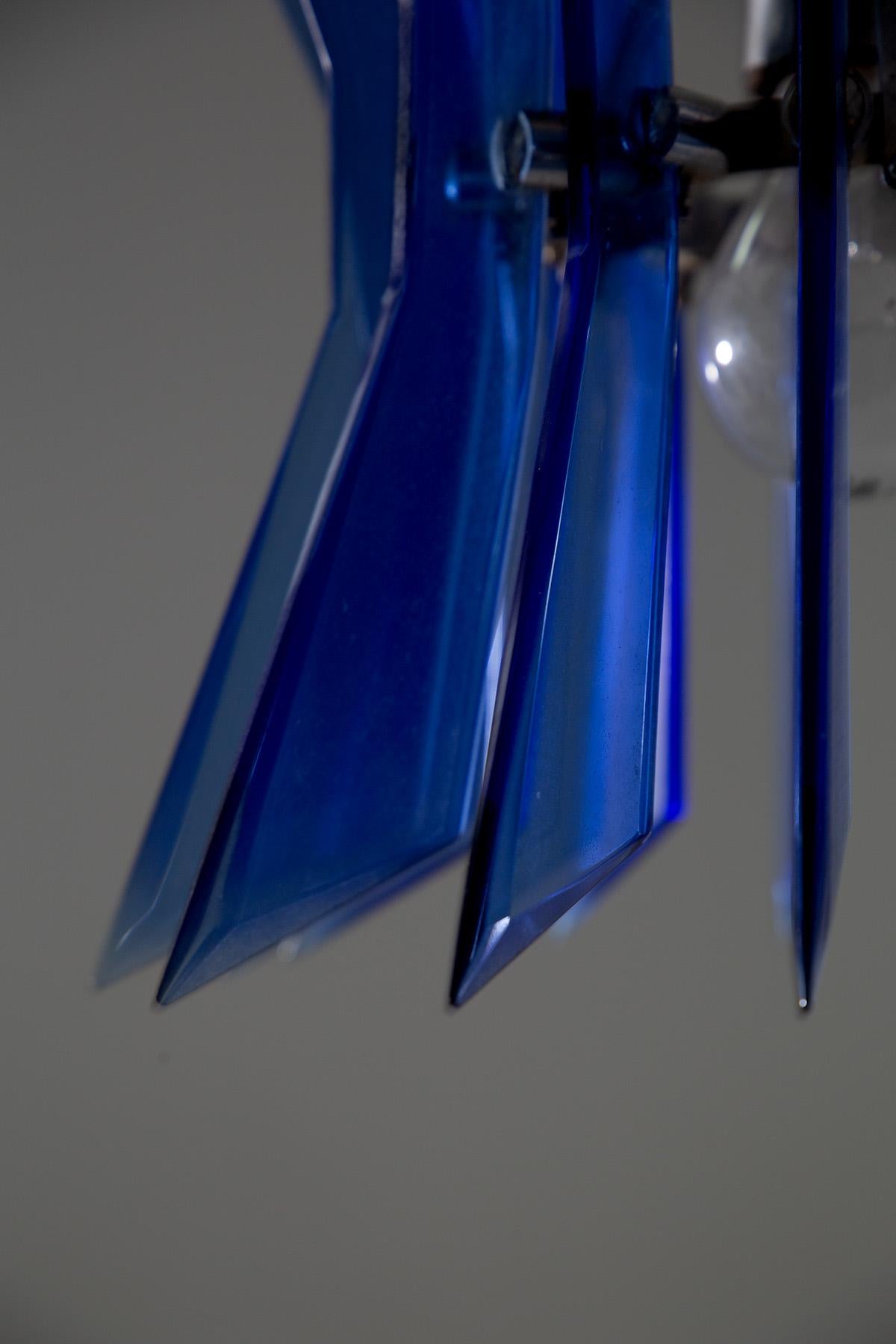 Cette lampe suspendue en verre bleu, datant des années 1970, témoigne de l'audace et de la sophistication du design italien de cette époque. Attribuée à Veca, une entreprise connue pour avoir façonné le style d'éclairage moderne avec ses créations,