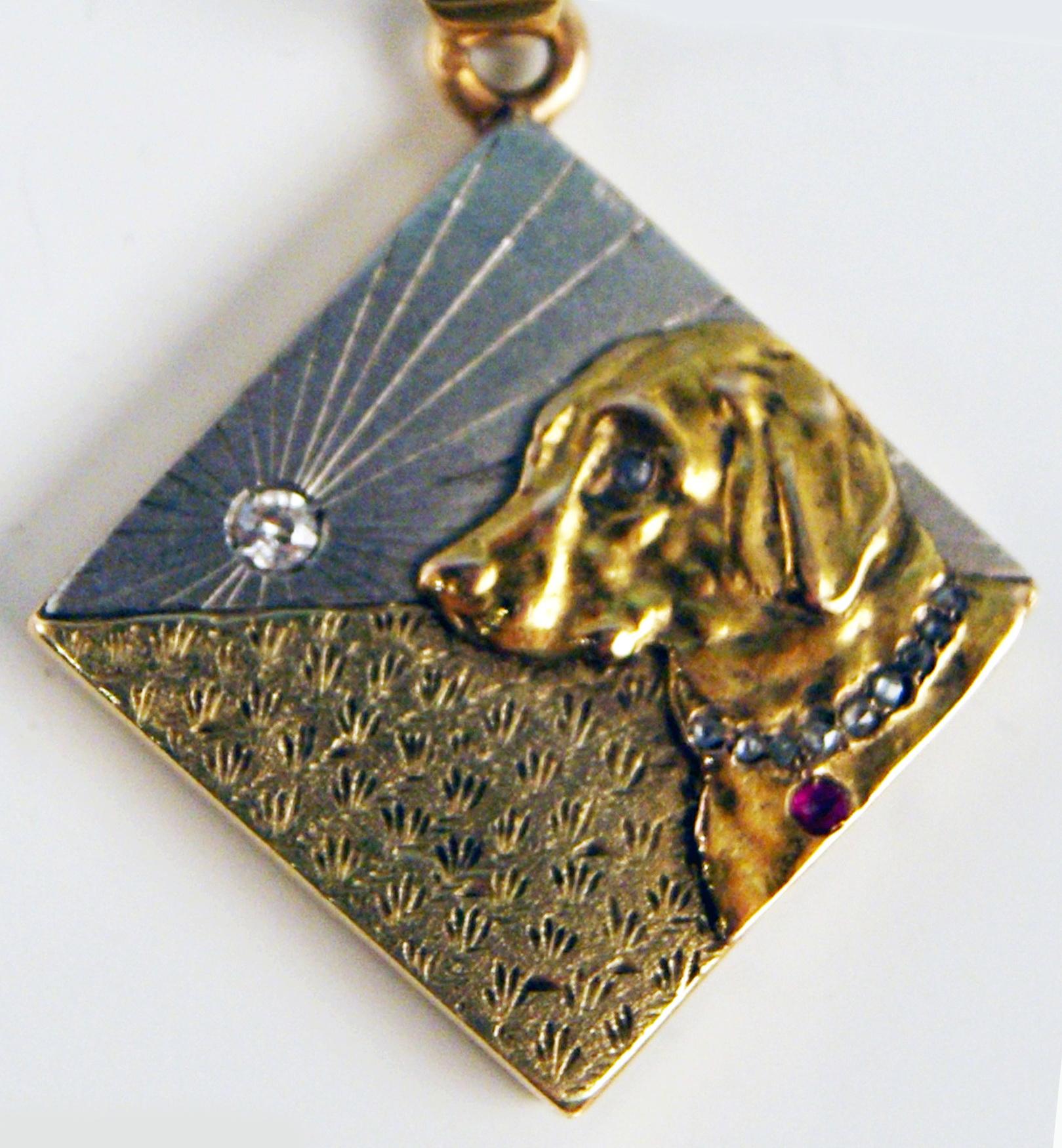 Very interesting pendant made during Viennese Art Nouveau Period: 
It is of square form type to which ten diamonds and a ruby are worked into surface. Further, there is a dog's head attached.
The sun is well visible in background, with a diamond in