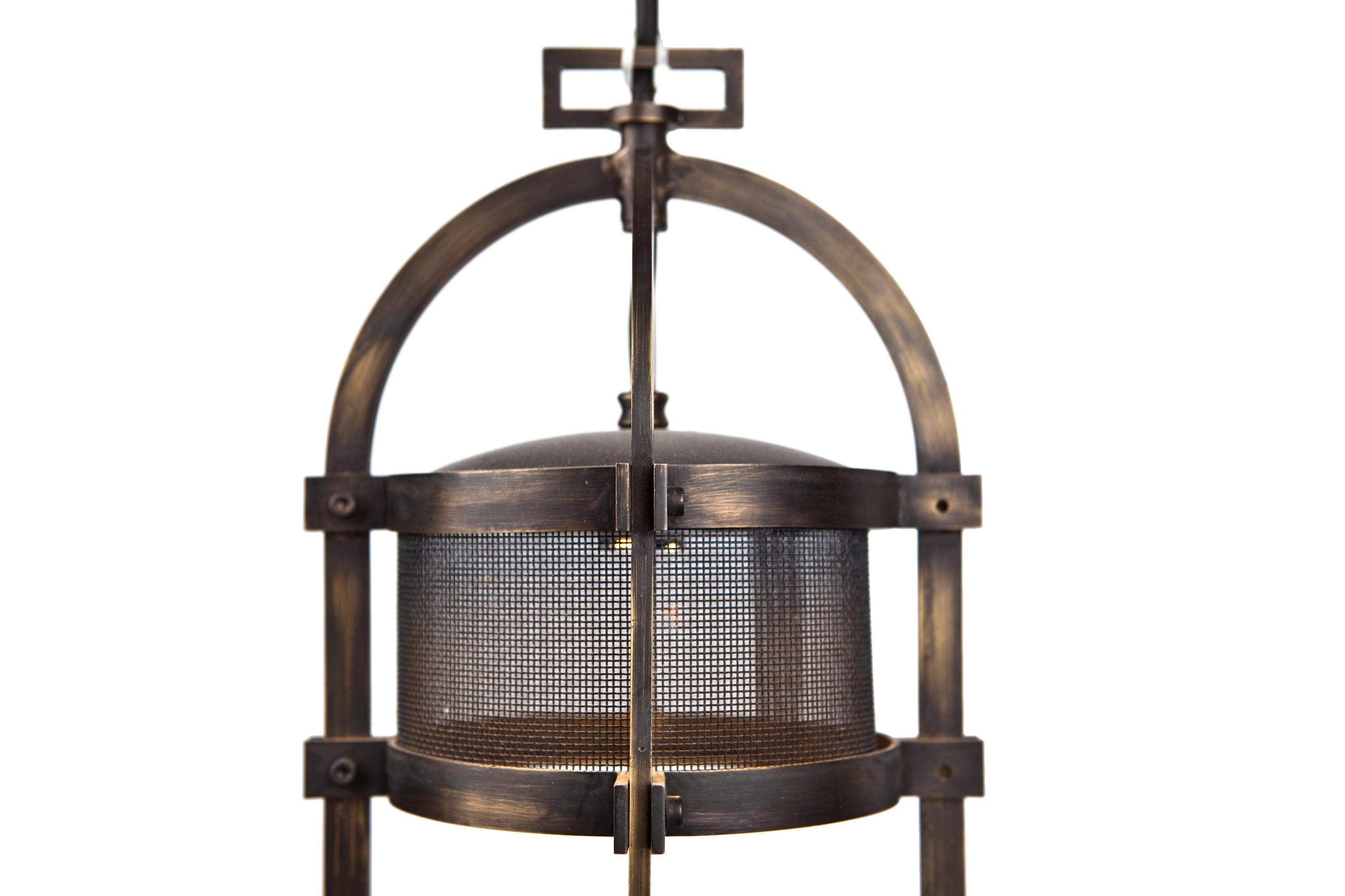 A pendant made of blackened brass with grid around the led patine.