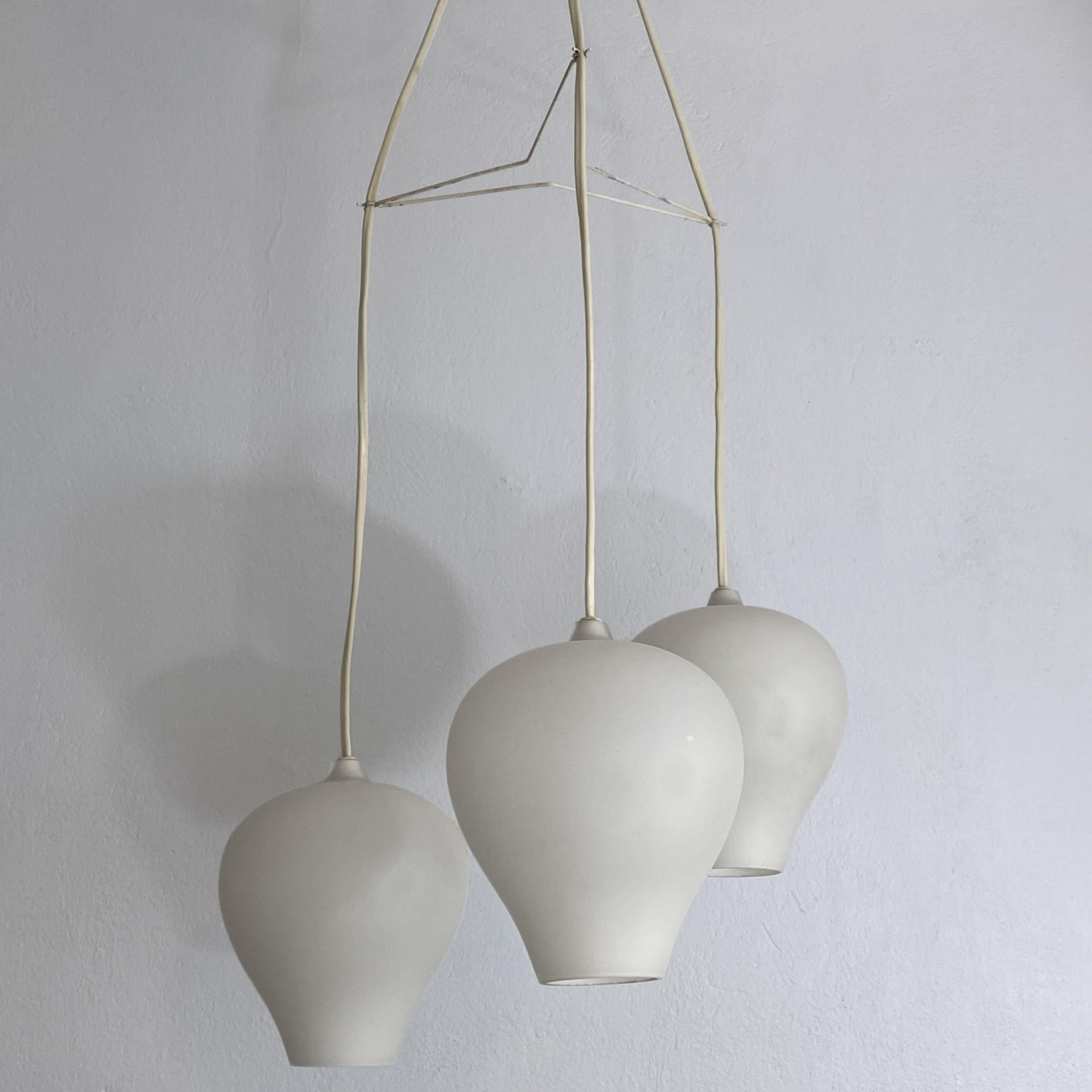 Pendant lamp designed by Alf Svensson for the renowned Swedish manufacturer Bergboms in 1953. This exquisite design features minimalist aesthetics with three clock-shaped opaline glass shades interconnected by a metal wire star. It is complemented