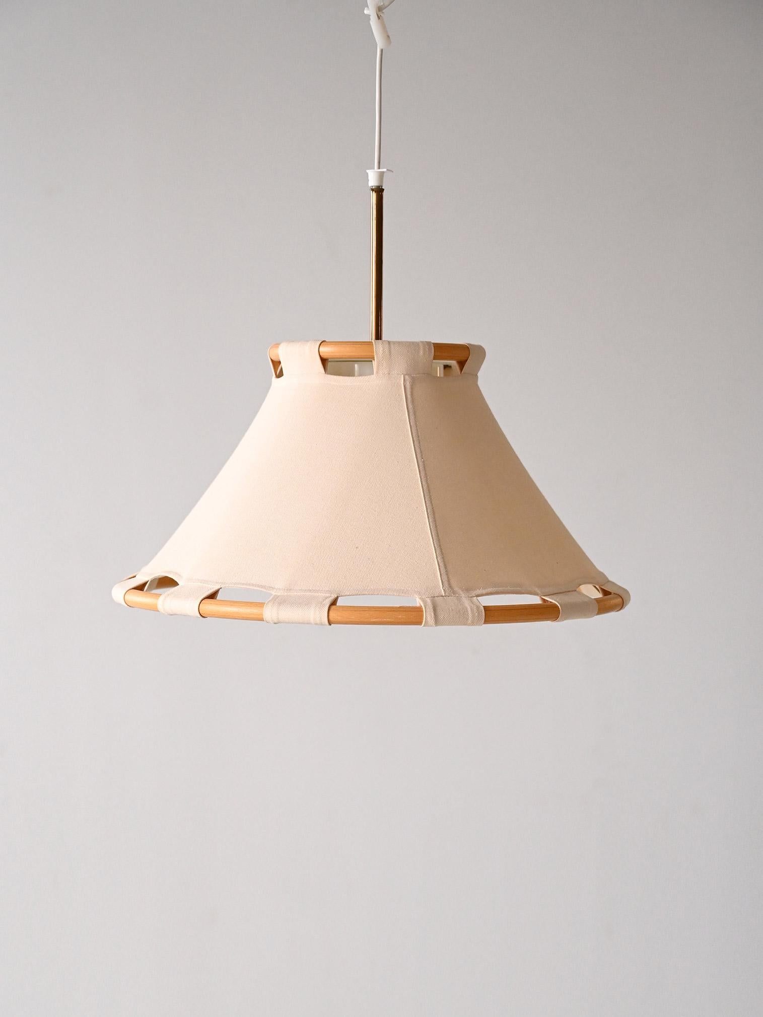 Vintage lamp designed for Ateljé Lyktan in the 1970s.

This piece of original Scandinavian design is an elegant mix of different materials, the shade is made of canvas, the frame is made of bamboo and the light is filtered by a plexiglass sheet.
A