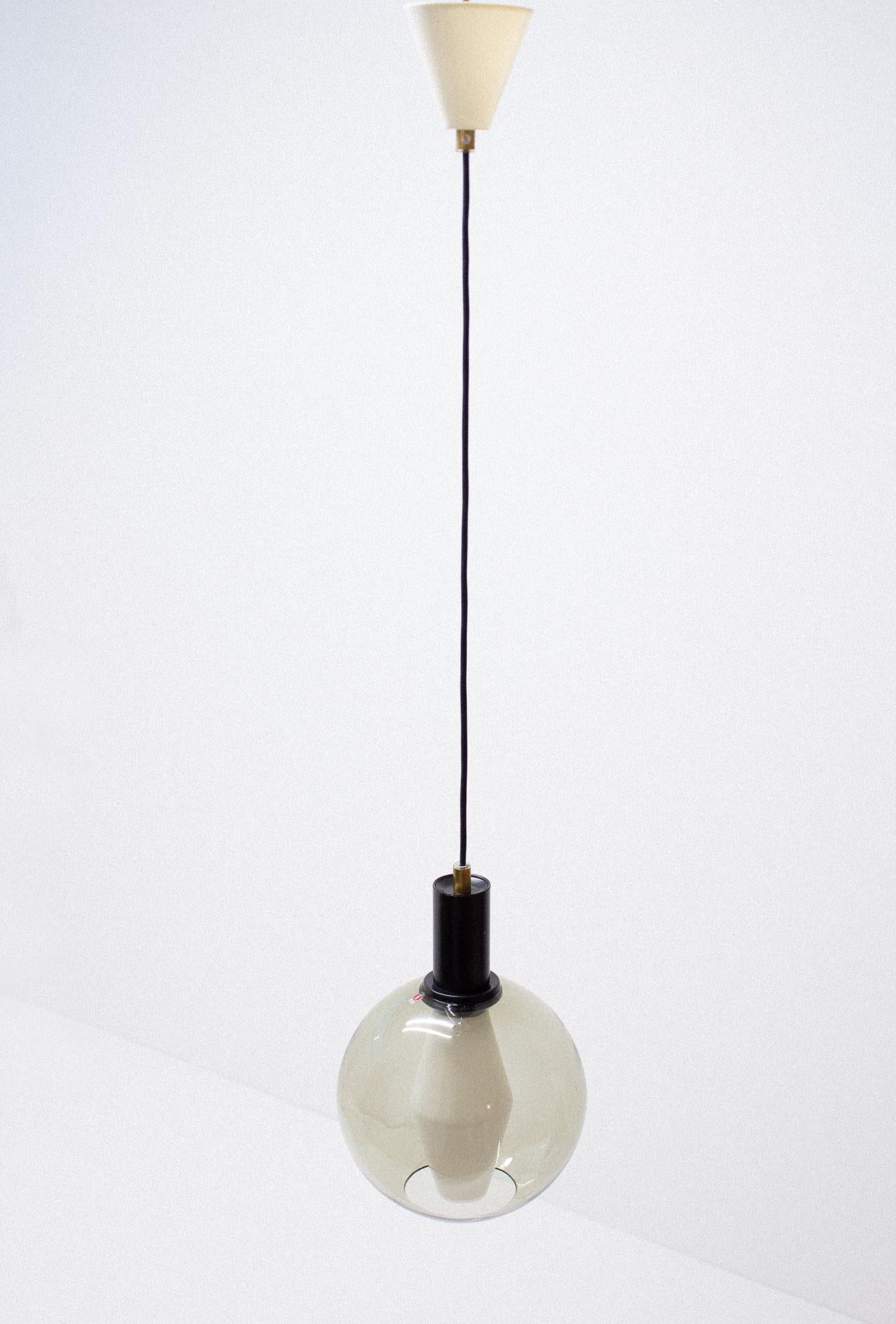 Hanging lamp designed by Tapio Wirkkala in Finland during the late 1950s. This actual pendant has been manufactured by Iittala during the 1970s. Blown glass ball slightly colored in smoked green with a metal and brass fitting. Original AIRAM bulb