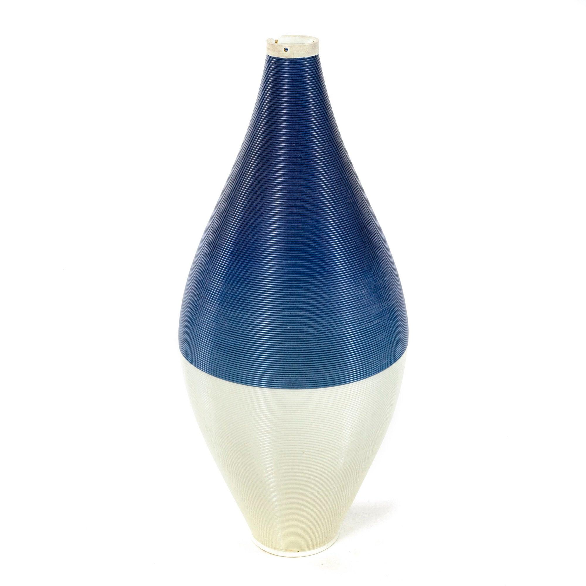 Una lampada a sospensione realizzata con corde di plastica continue che si intrecciano in un apparecchio da soffitto a forma di cono. Il cavo bianco e blu emette una luce calda quando è acceso.