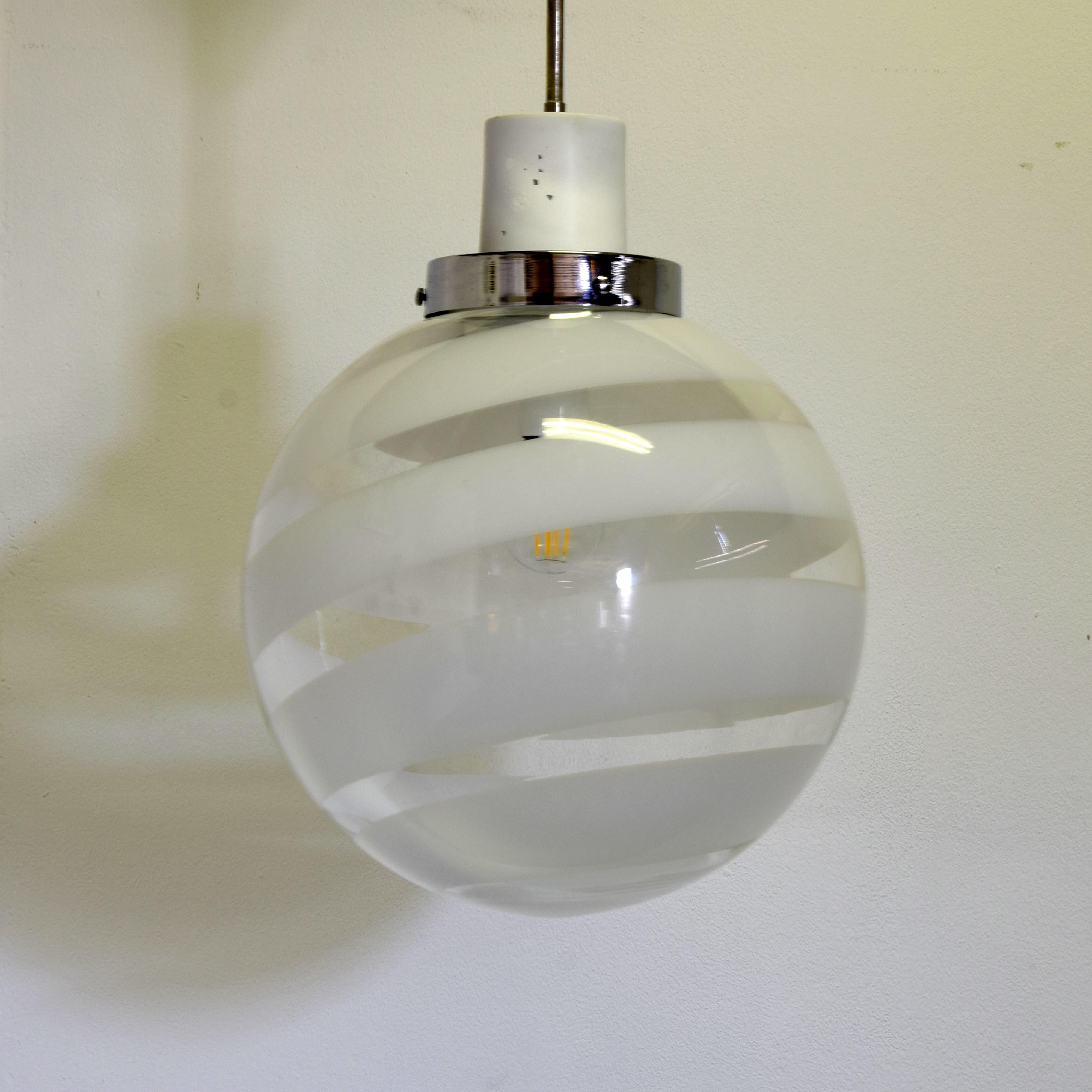 An elegant pendant lamp produced by Venini in 1970, a representative example of Italian design and the refined Murano glass art of the period.

The diffuser is made of transparent blown glass, characterised by lattimo bands (white opaline glass),