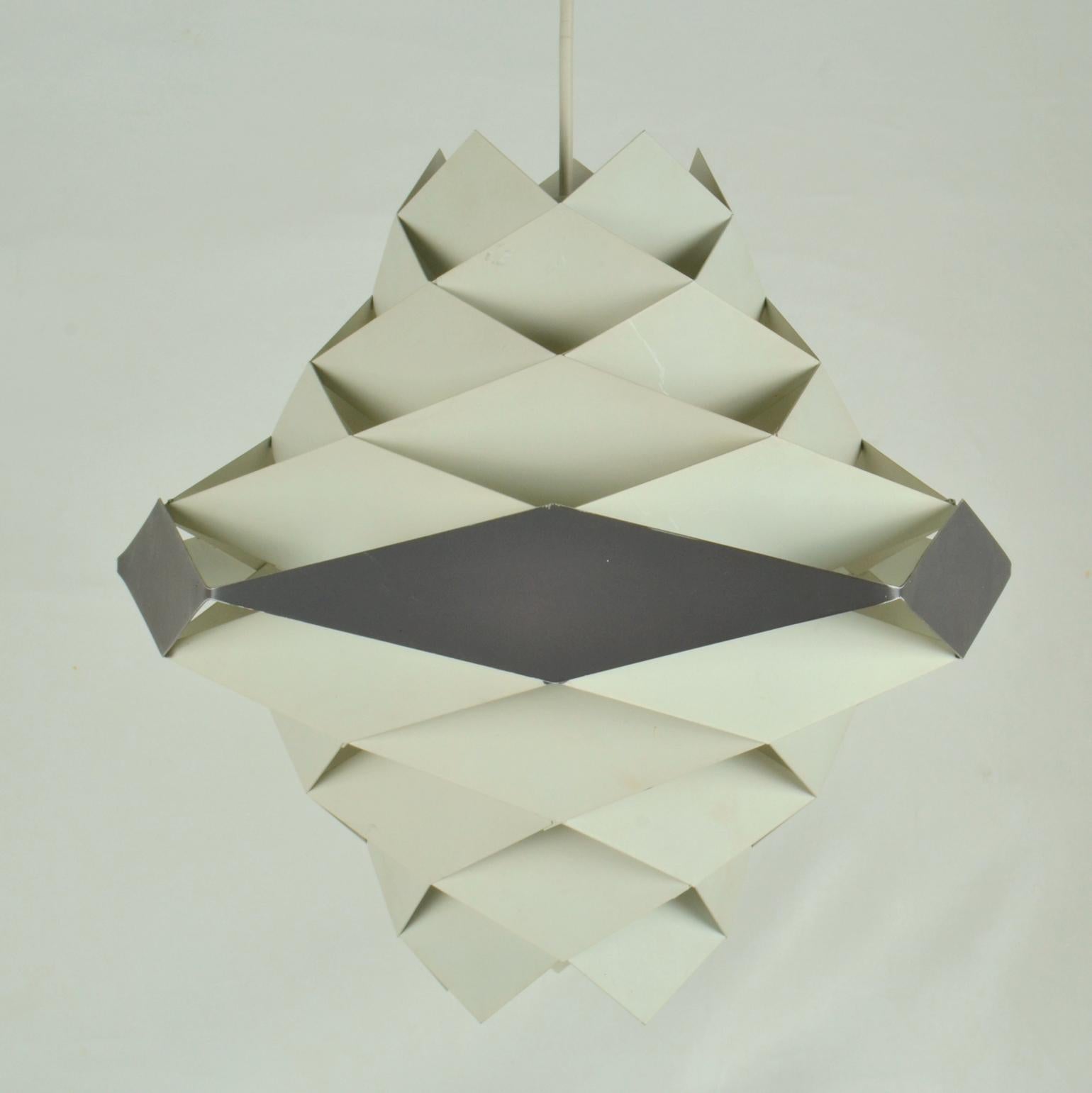 Die Leuchte Symfoni aus weiß und dunkelgrau-schwarz lackierten Metalldiamanten, die zu einem Lampenschirm im Origami-Stil montiert sind, wurde von Preben Dal (1929-1980) entworfen und von Hans Følsgaard Elektro hergestellt.
Symfoni-Lampen wurden in