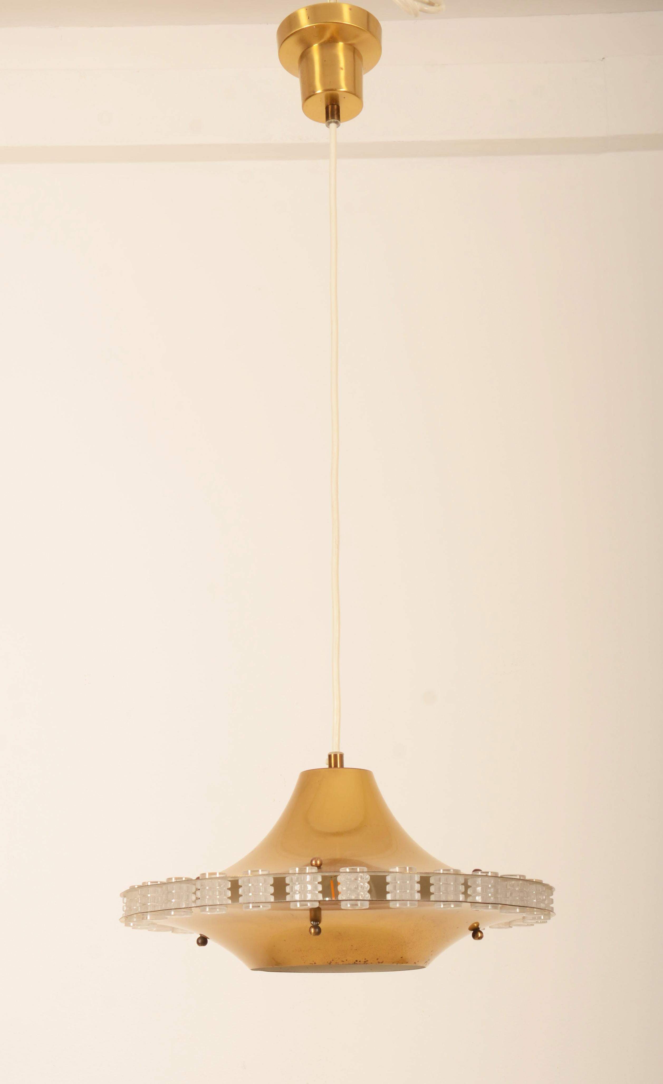 Deckenlampe aus Messing mit durchbrochenem Glasdekor. Deckentasse mit der Aufschrift Philips.
Berichten zufolge wurde ein Prototyp für Ateljé Lyktan entwickelt, der jedoch nicht in Produktion ging.
Abmessungen Lampe allein: Ø 35 cm, Höhe 18 cm.