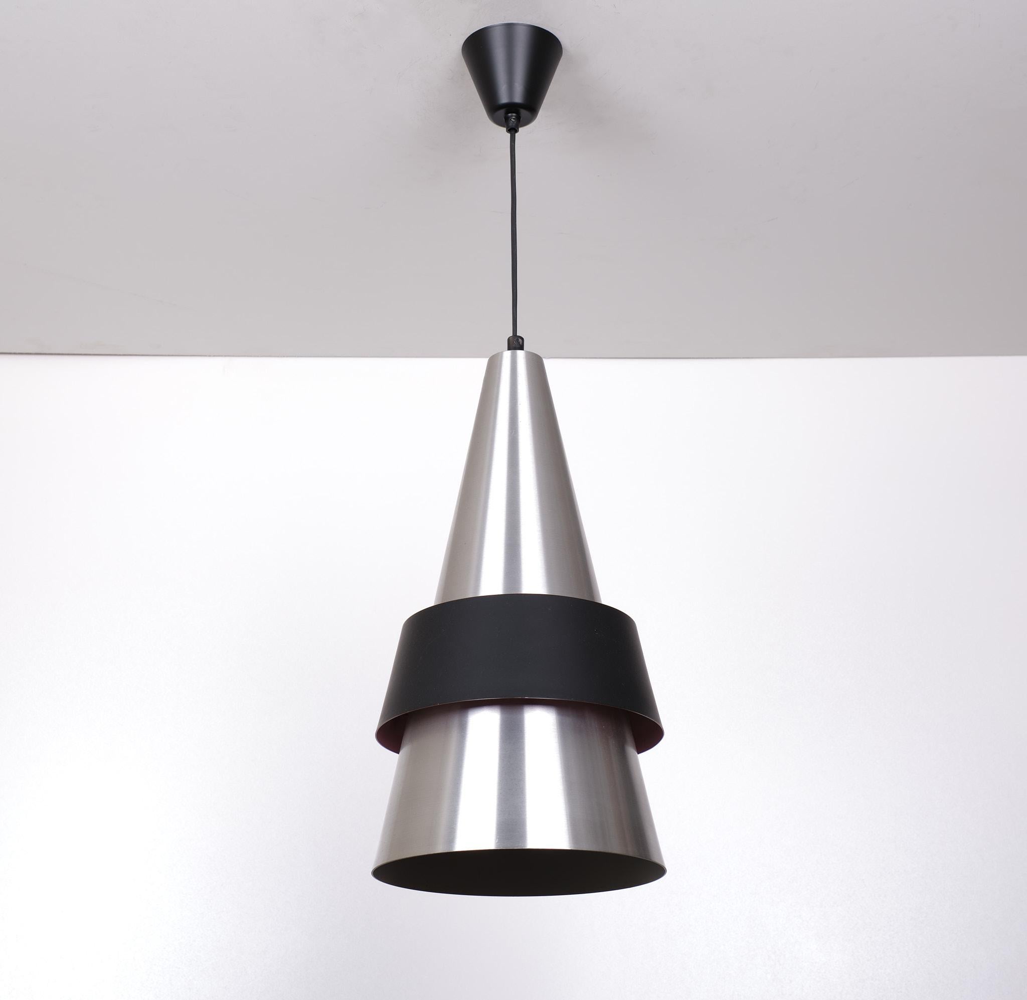 This large conical pendant lamp is made from brushed aluminum with a matte black shade. The model is called Corona, it was designed by Jo Hammerborg, and was manufactured by Fog & Morup in the early 1960s.  Good condition .
rewired .