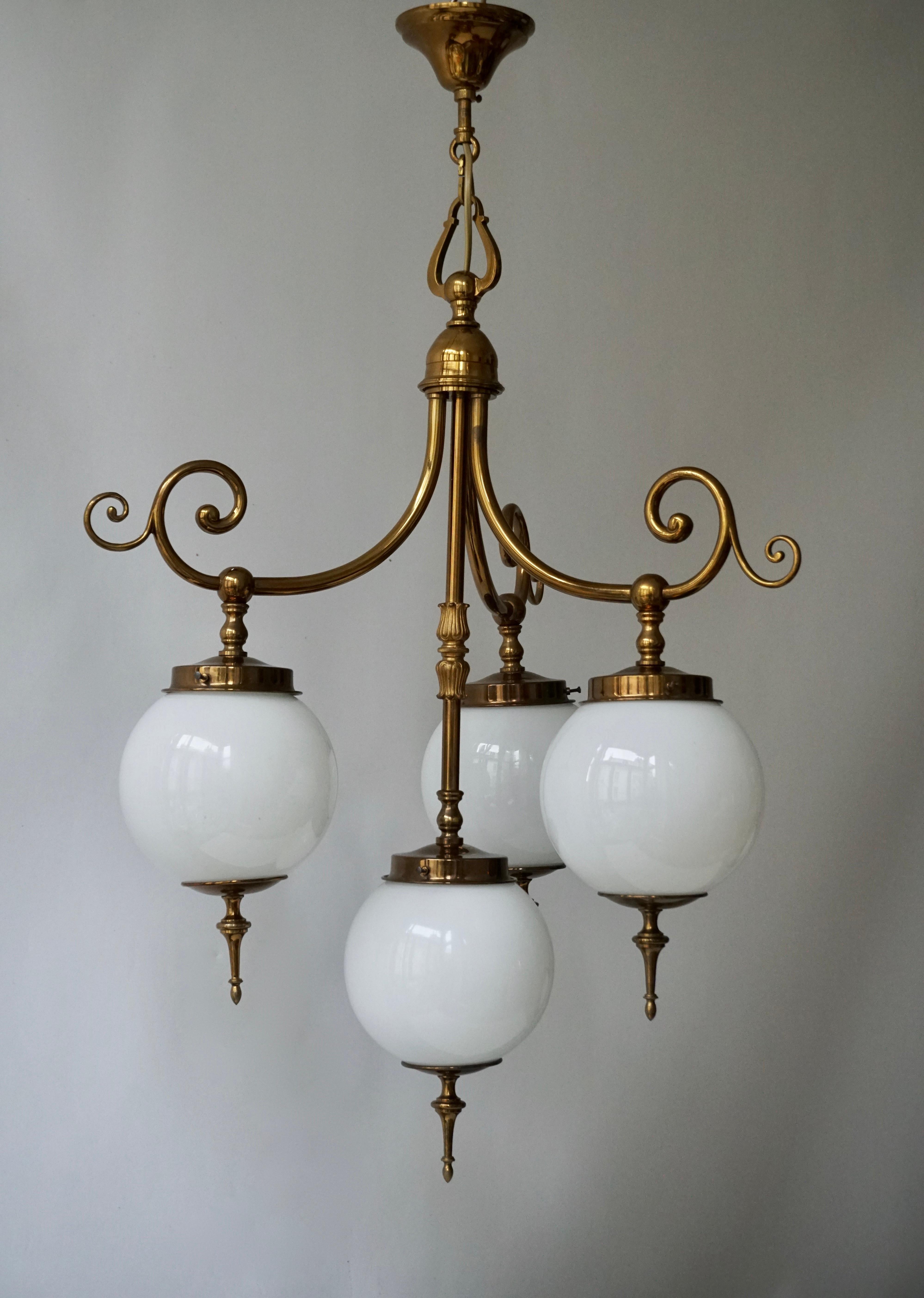 Very elegant Italian midcentury chandelier, circa 1950. 
It features an all brass structure with four white opaline glass shades.

Diameter 48 cm.
Height fixture 70 cm.
Total height including chain 83 cm.