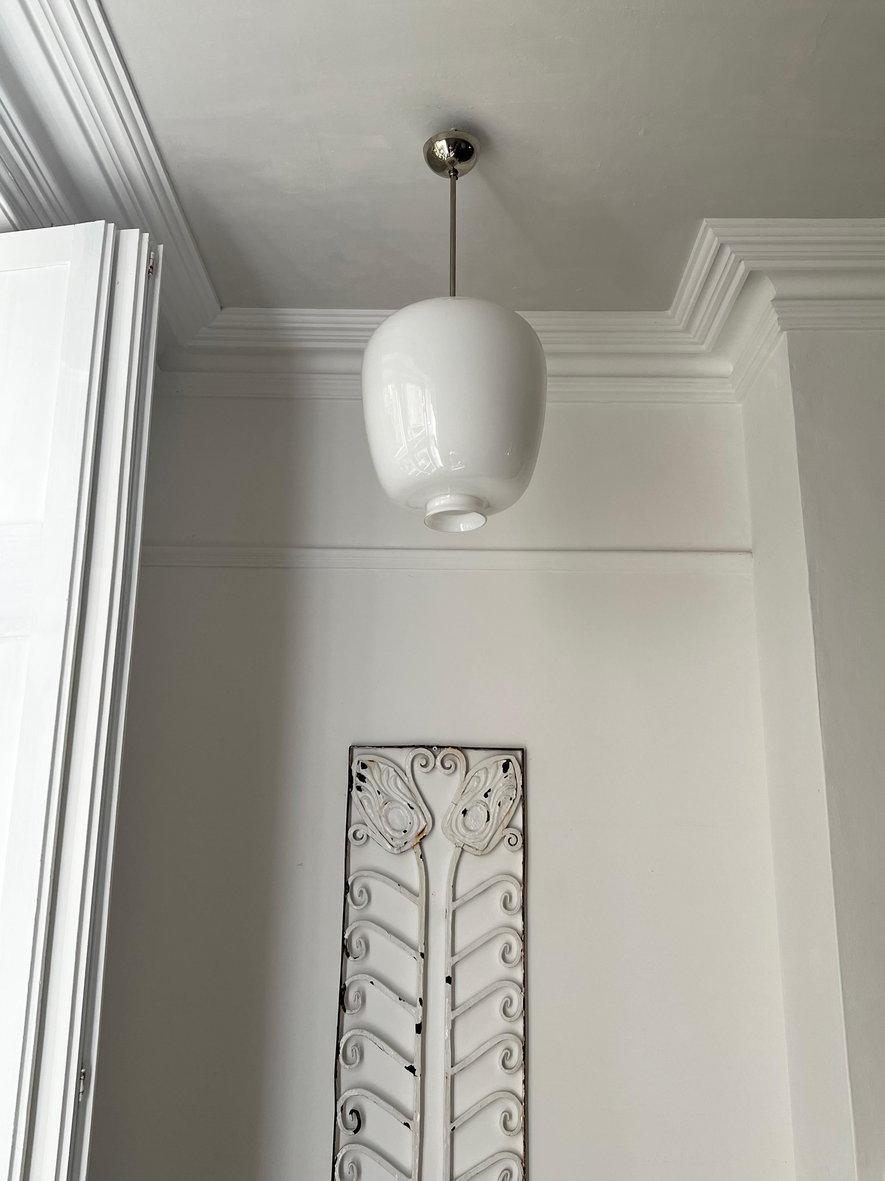 A simple and elegant pendant light with a white glass shade attributed to Pukeberg Glassworks of Sweden, first half twentieth century. 

The pendant features a generous oval shade, nicely made, with a simple chrome-finished stem and ceiling canopy.