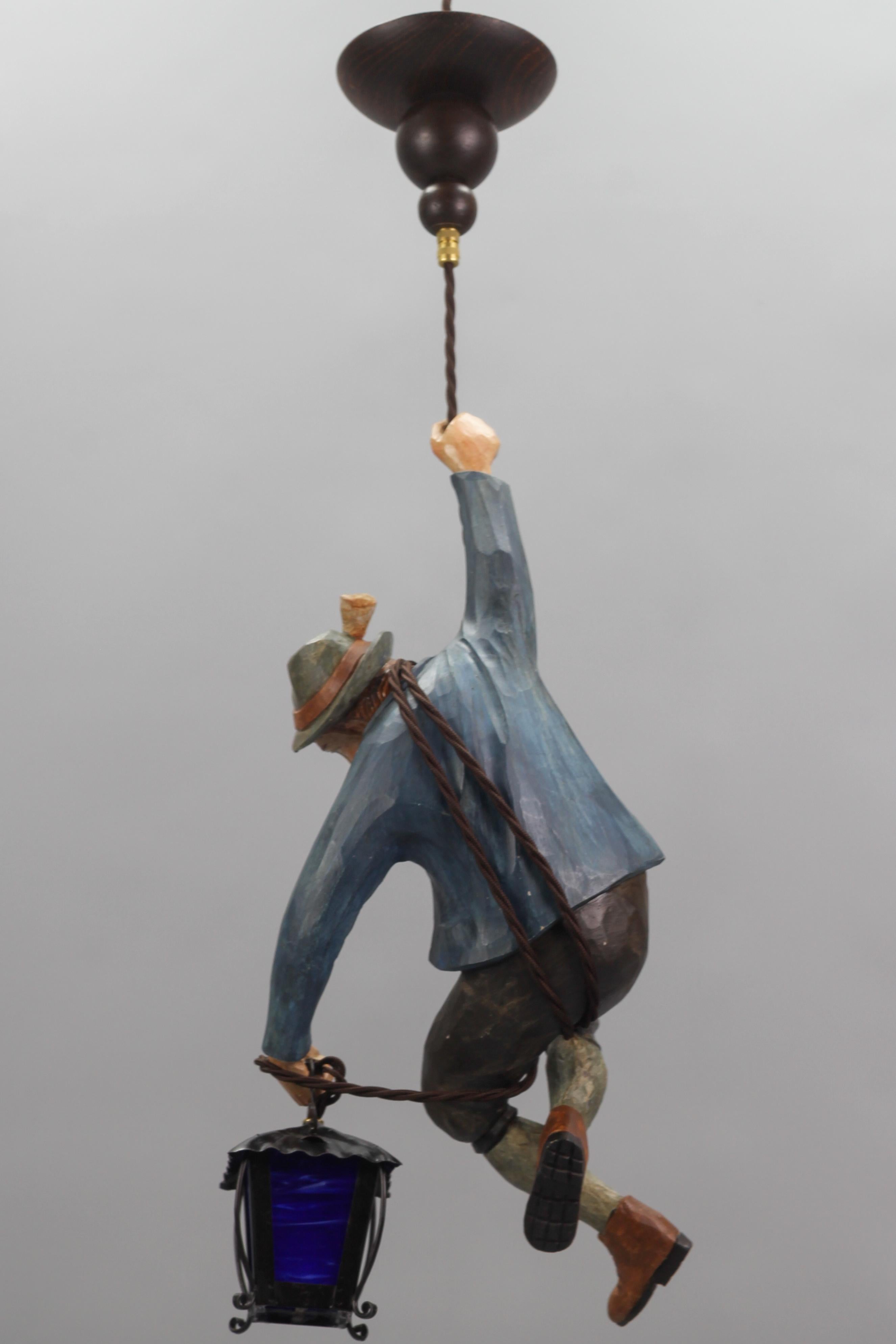 German Pendant Light with Figure of a Mountain Climber and a Blue Glass Lantern For Sale