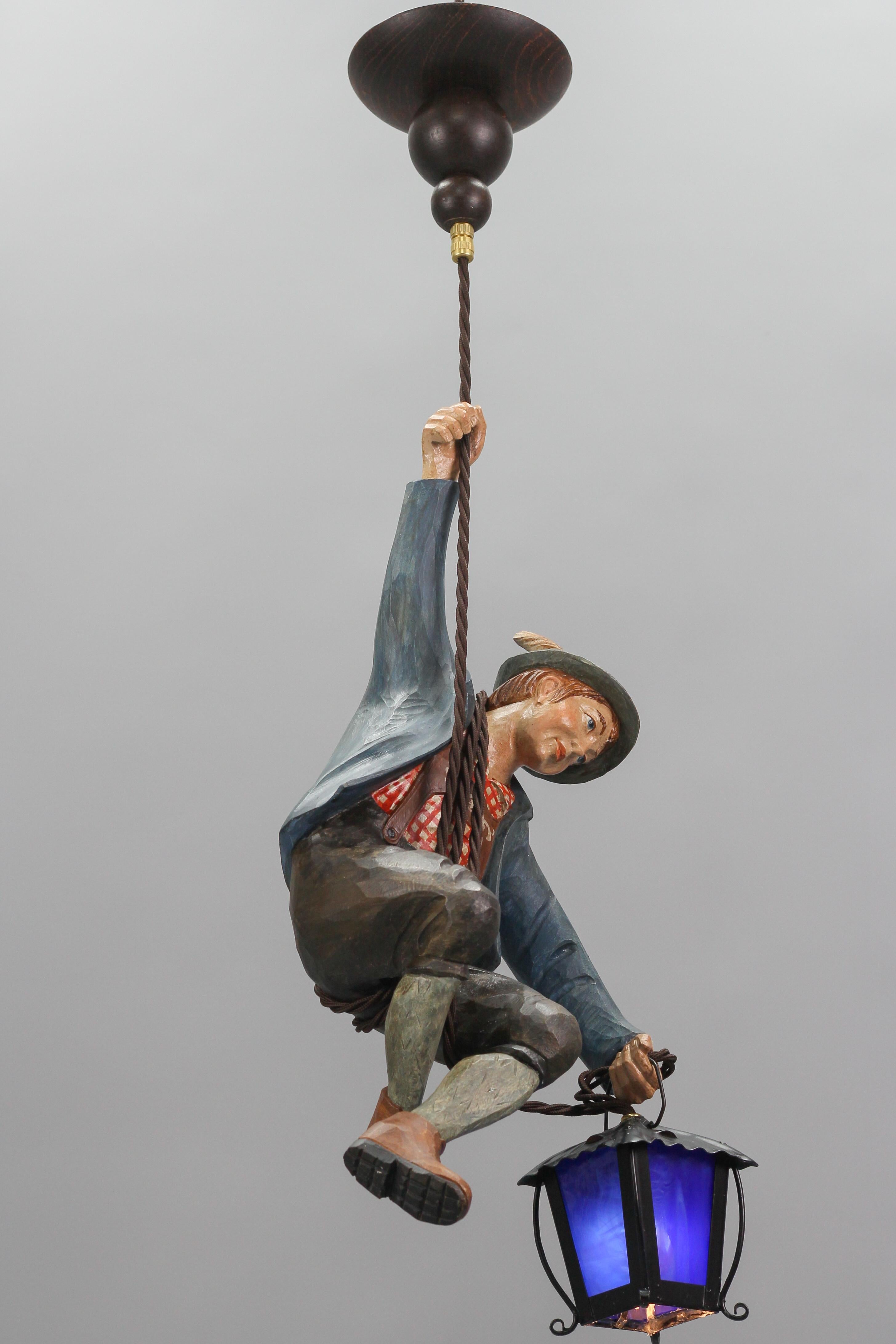 Metal Pendant Light with Figure of a Mountain Climber and a Blue Glass Lantern For Sale