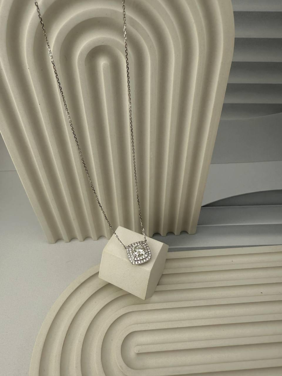 Dieser exquisite Anhänger ist sorgfältig aus 18 Karat Weißgold gefertigt und unterstreicht die außergewöhnliche Kunstfertigkeit und Qualität des feinen Schmuckdesigns. In seinem Zentrum befindet sich ein Diamant im Kissenschliff mit einem Gewicht