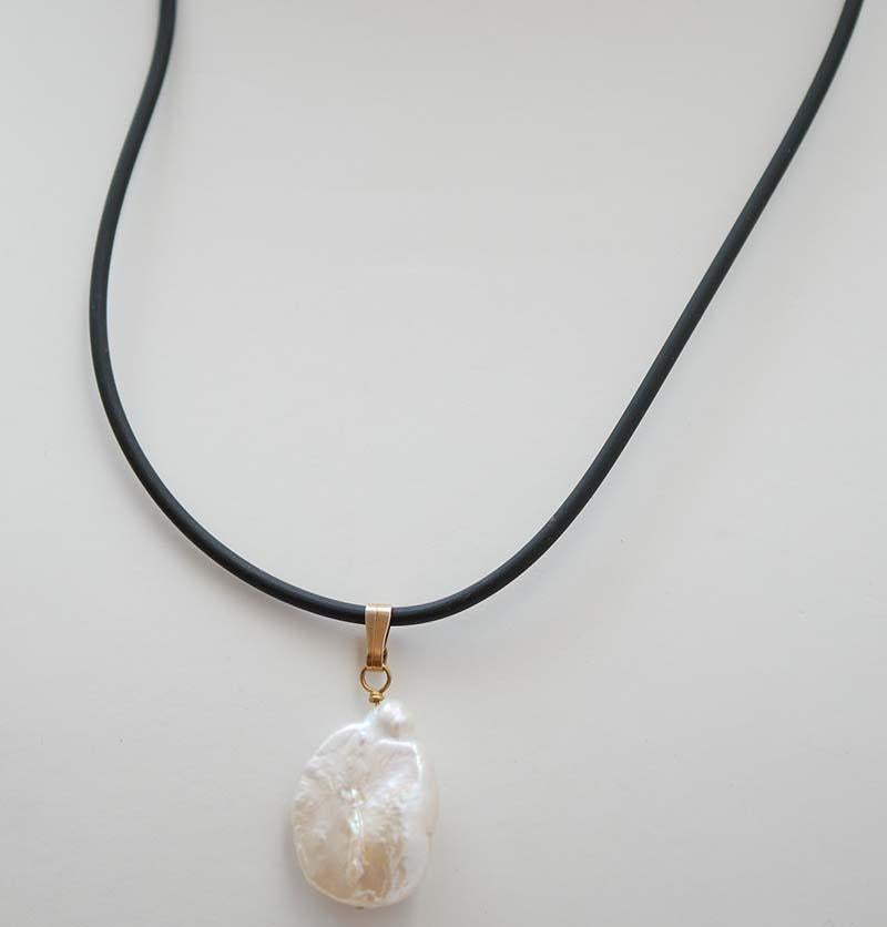 Pendant with a pearl and a rubber chain.