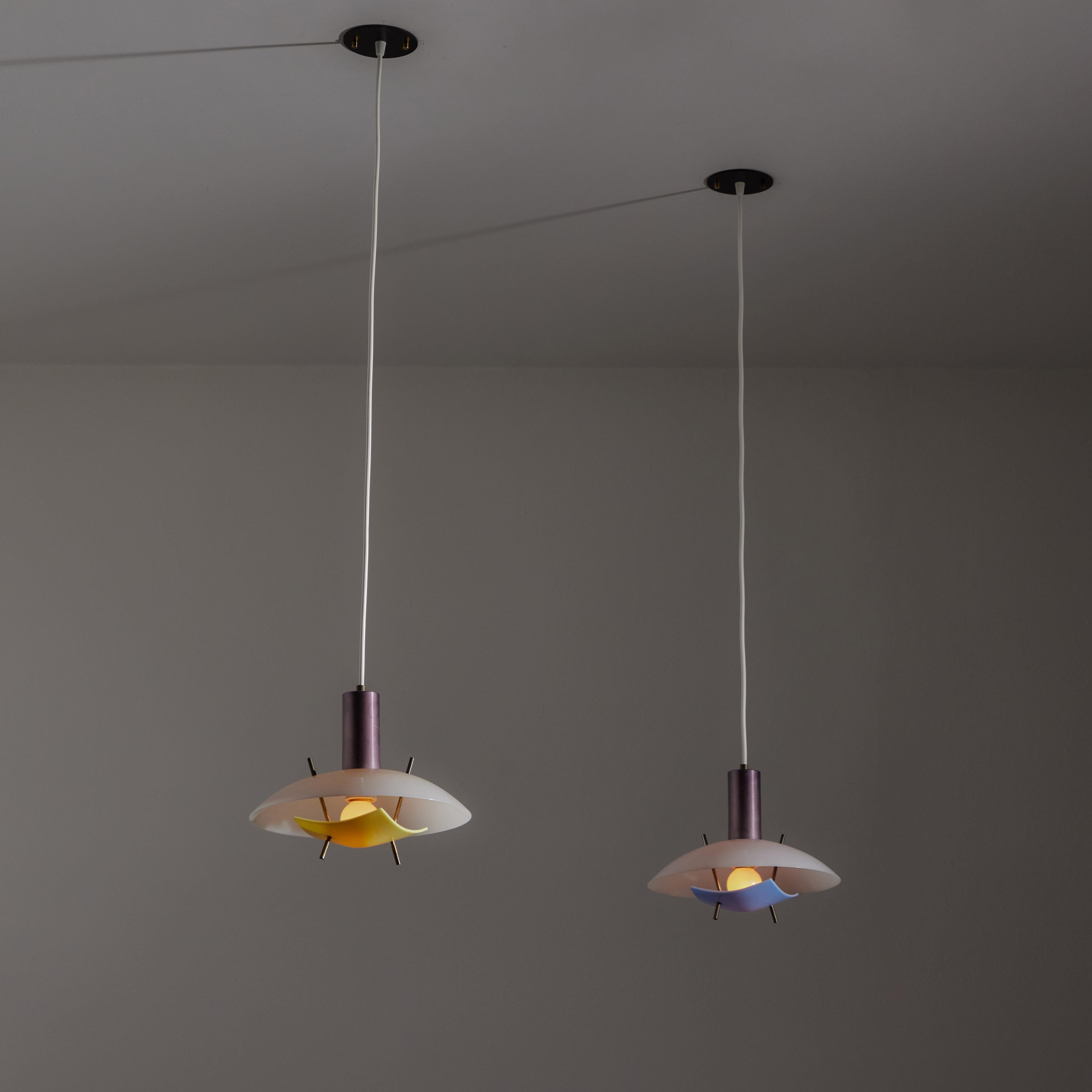 Pendants by Arredoluce. Designed and manufactured in Italy, circa the 1960s. White acrylic upper shade, paired with a colored acrylic diffuser at the bottom. Burnished and patinated brass details. Each pendant holds a singel E27 socket type, adapted