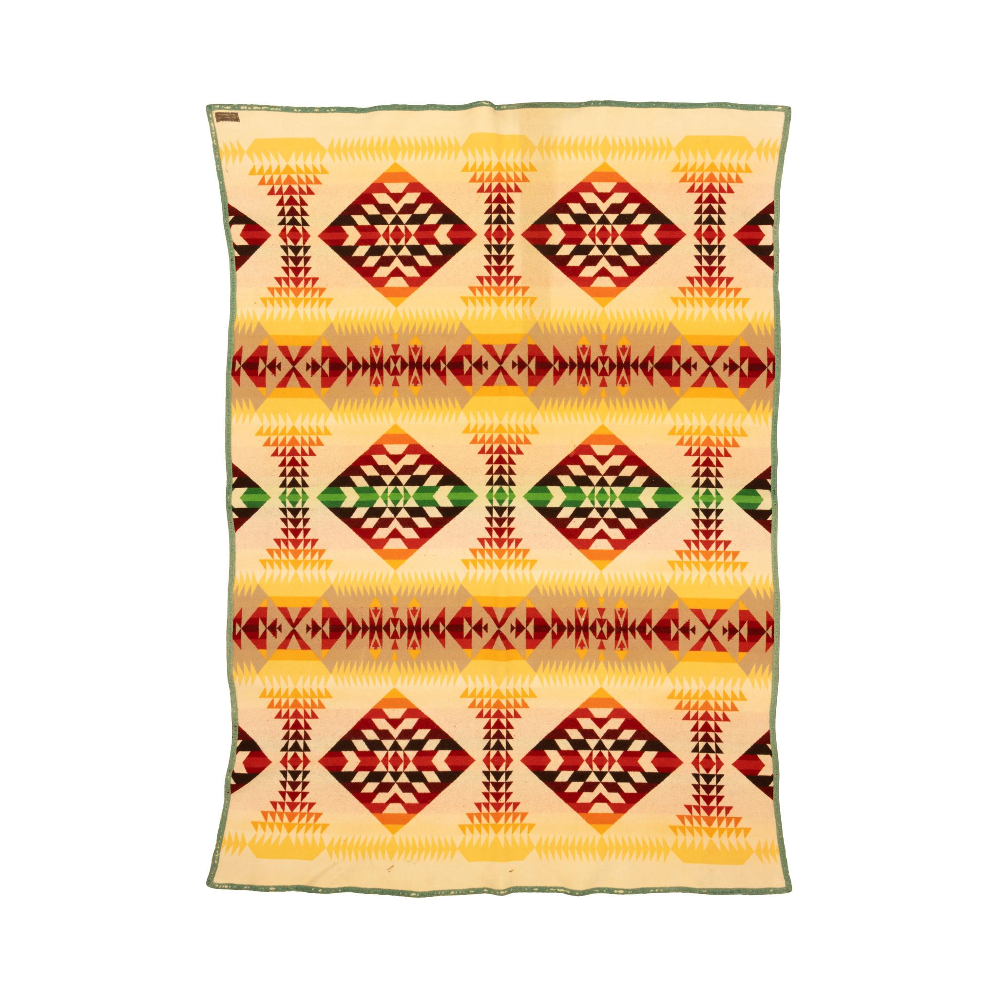 Coperta commerciale in lana double-face di Pendleton con rilegatura bordata ed etichetta. Caratterizzato da colori caldi e brillanti di rosso, verde, giallo e marrone su uno sfondo ombreggiato a bande. Disegni geometrici a bande e cristalli. Inizio